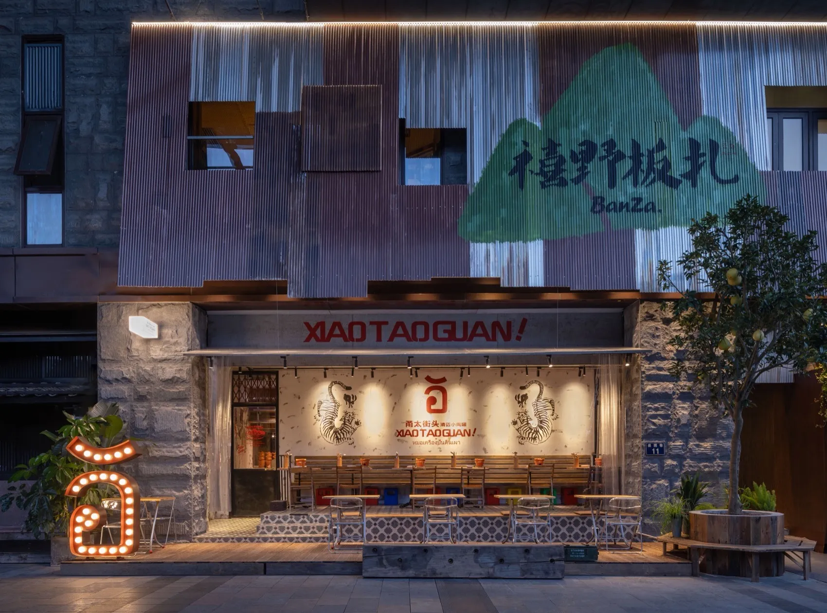 A modern Asian restaurant with a mountain theme, featuring a large dining area with multiple tables, benches, and warm lighting