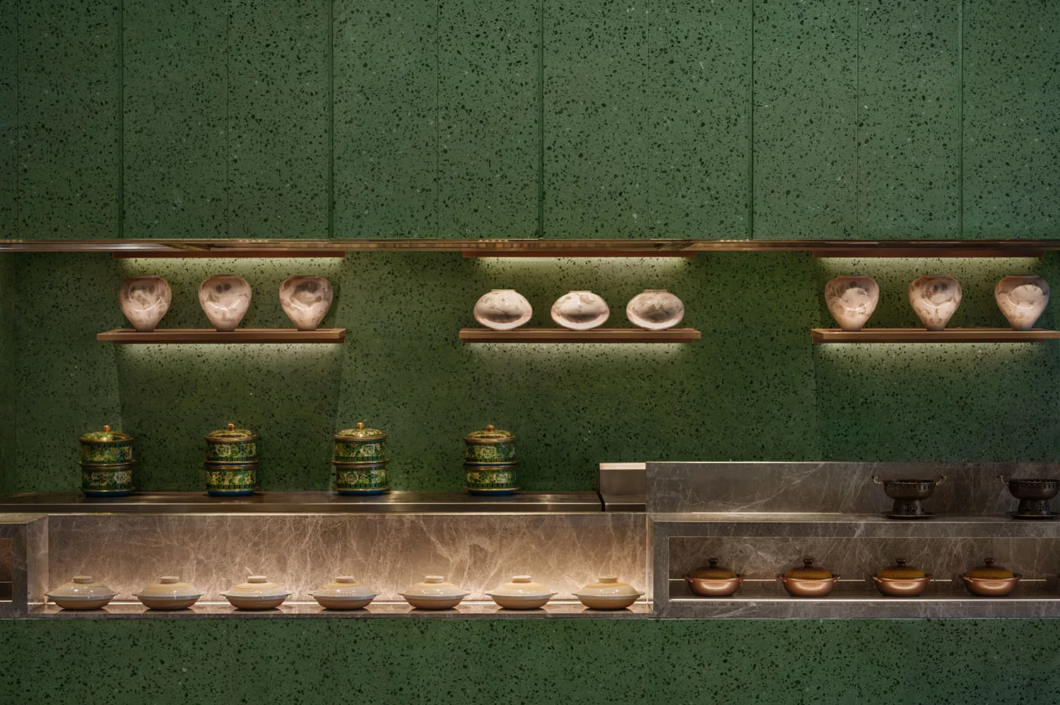 A clean and organized kitchen with green walls and a countertop featuring variously sized bowls and two cups, emphasizing functionality and practicality
