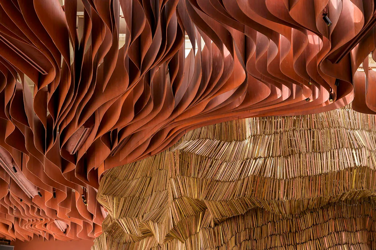 A wooden structure in a cozy space with variously sized books stacked in different orientations, creating a unique display