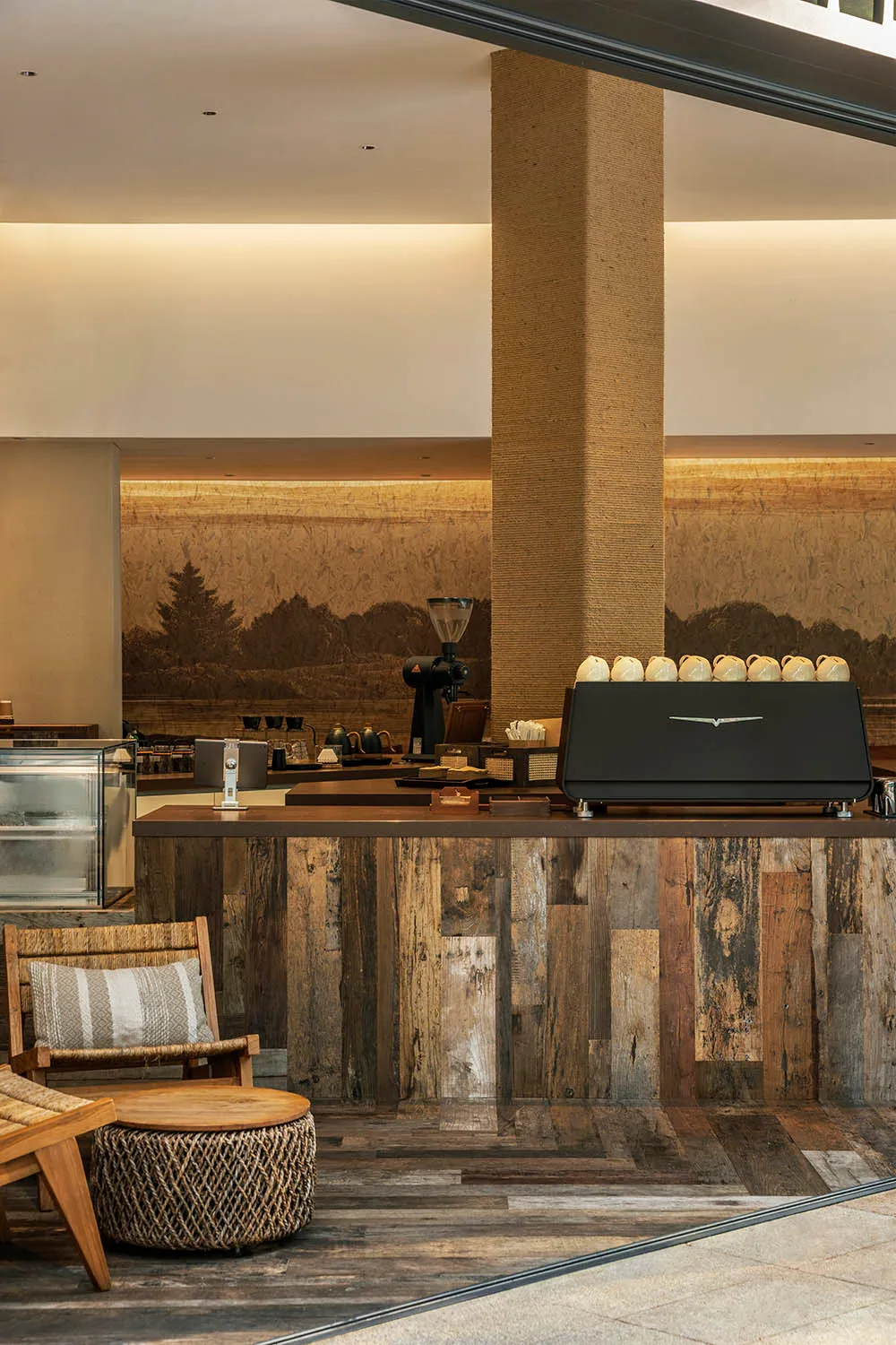 Warm and inviting coffee shop interior with a wooden countertop, black espresso machine, and several cups on the counter
