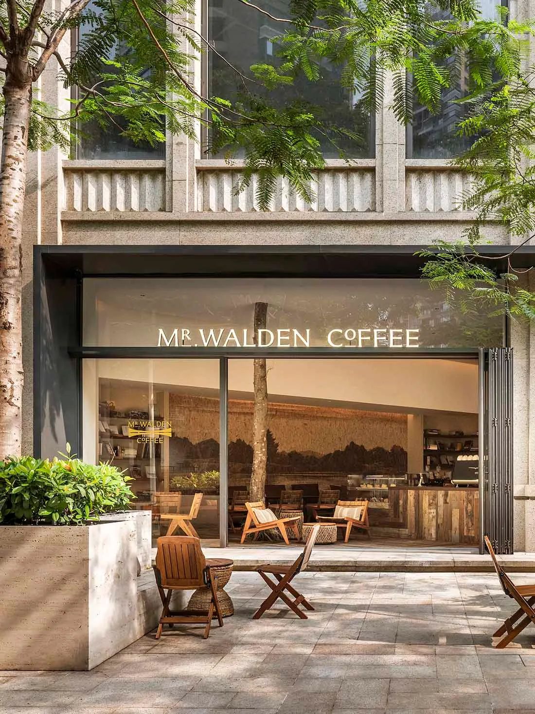 A relaxed outdoor cafe with wooden chairs and tables, accompanied by benches, set in front of a building