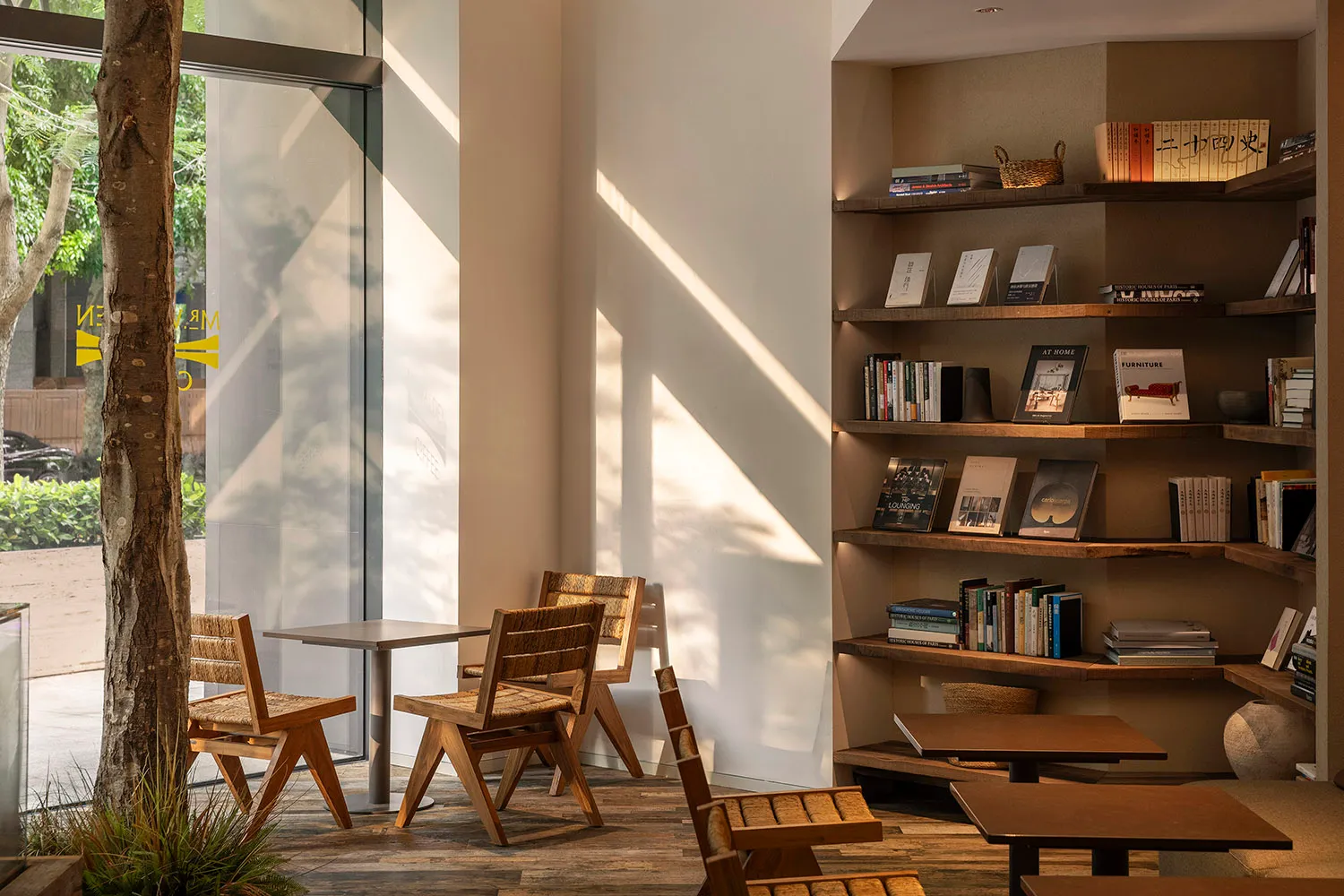 Cozy modern living space with a dining table, chairs, bookshelves, and a window, featuring clean lines and neutral tones
