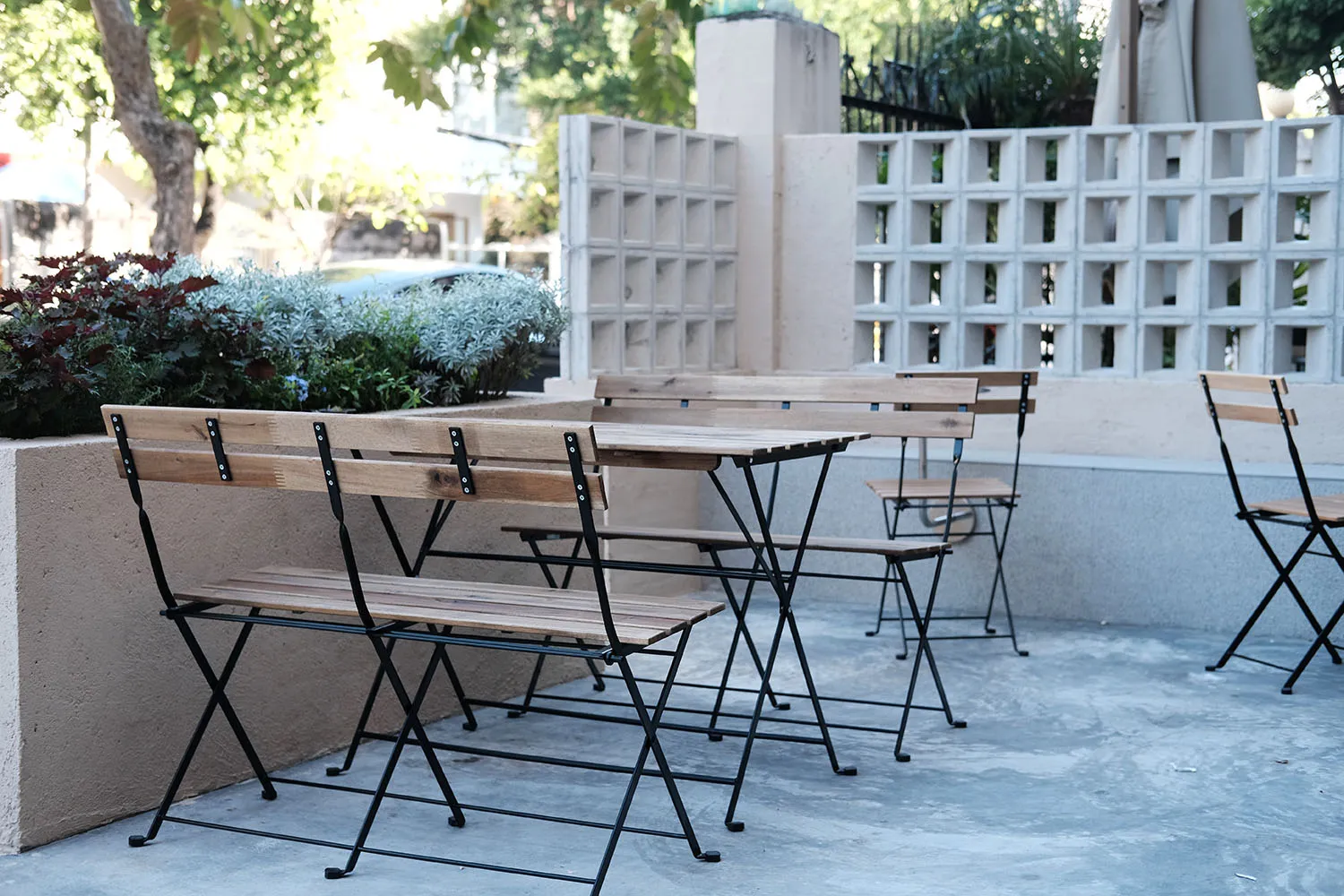 Outdoor patio area with wooden tables and metal chairs, inviting atmosphere, perfect for socializing or meals