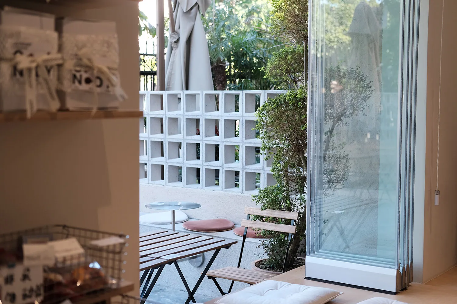 A relaxed indoor patio area with three chairs, two dining tables, and potted plants, creating a warm and inviting atmosphere
