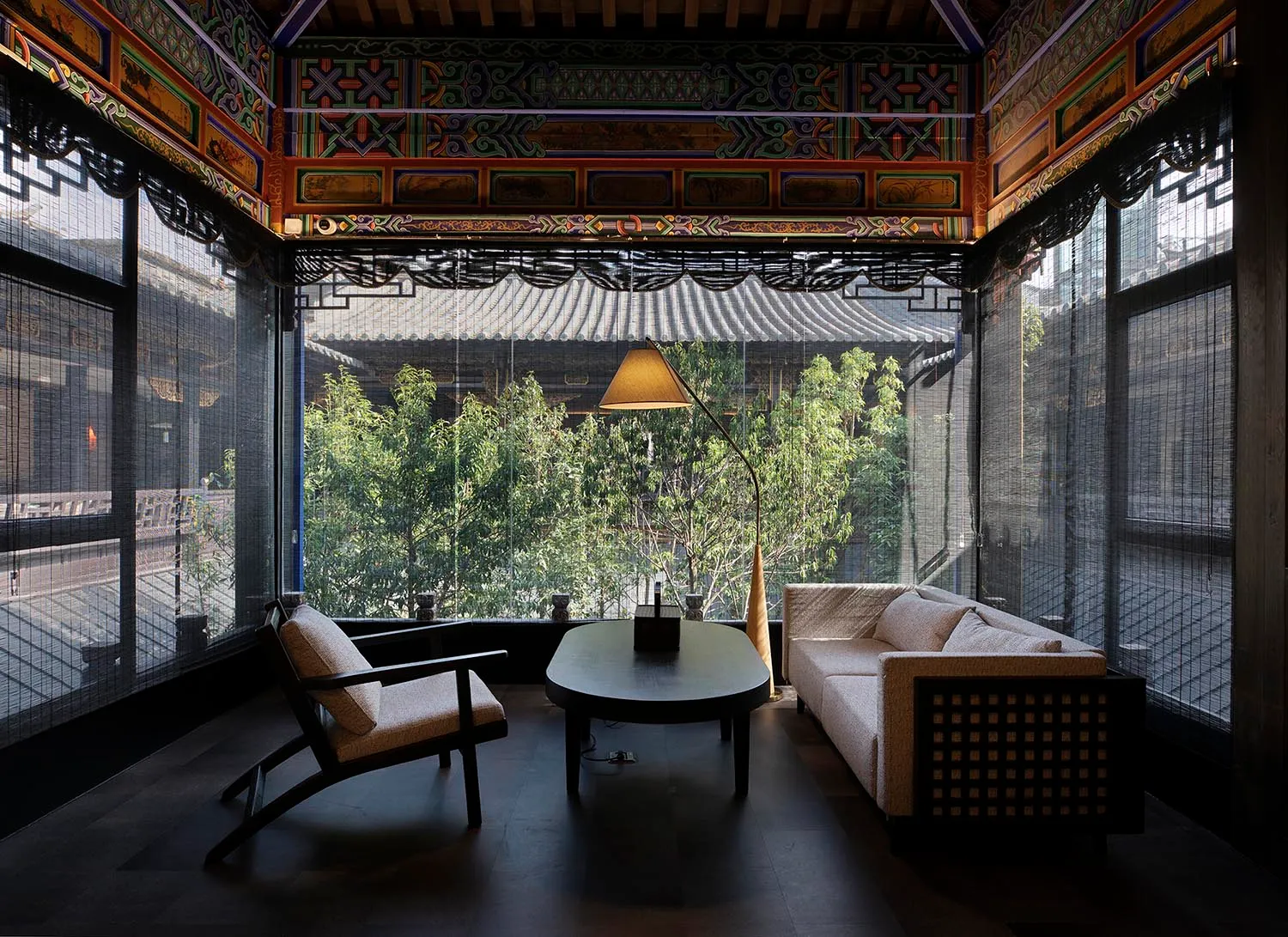 Asian-style living room with a large window, two couches, a chair, a dining table, and a potted plant, creating a warm and inviting atmosphere with a focus on comfort and relaxation