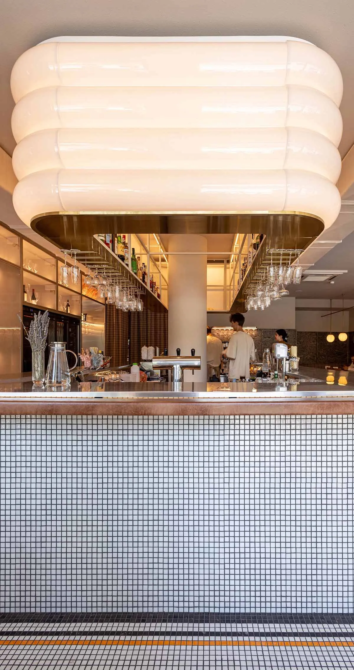 A cozy bar area with a long counter featuring wine glasses and two cups, creating a relaxed atmosphere for socializing