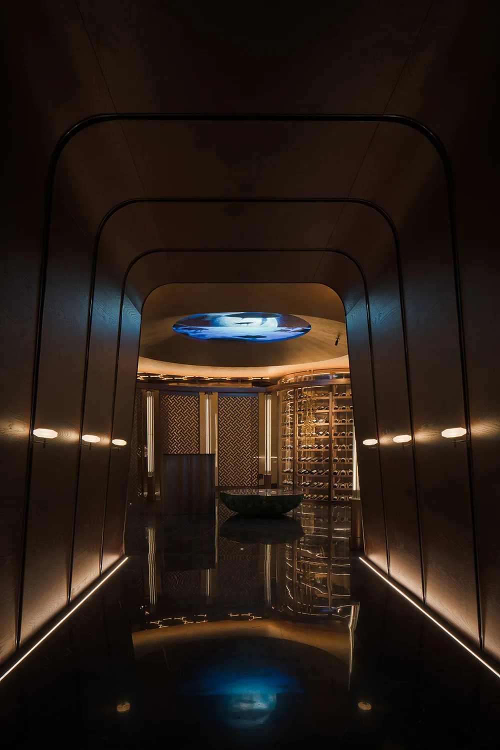 A dimly lit hallway with a row of wine bottles on a counter, suggesting a winery or wine storage facility