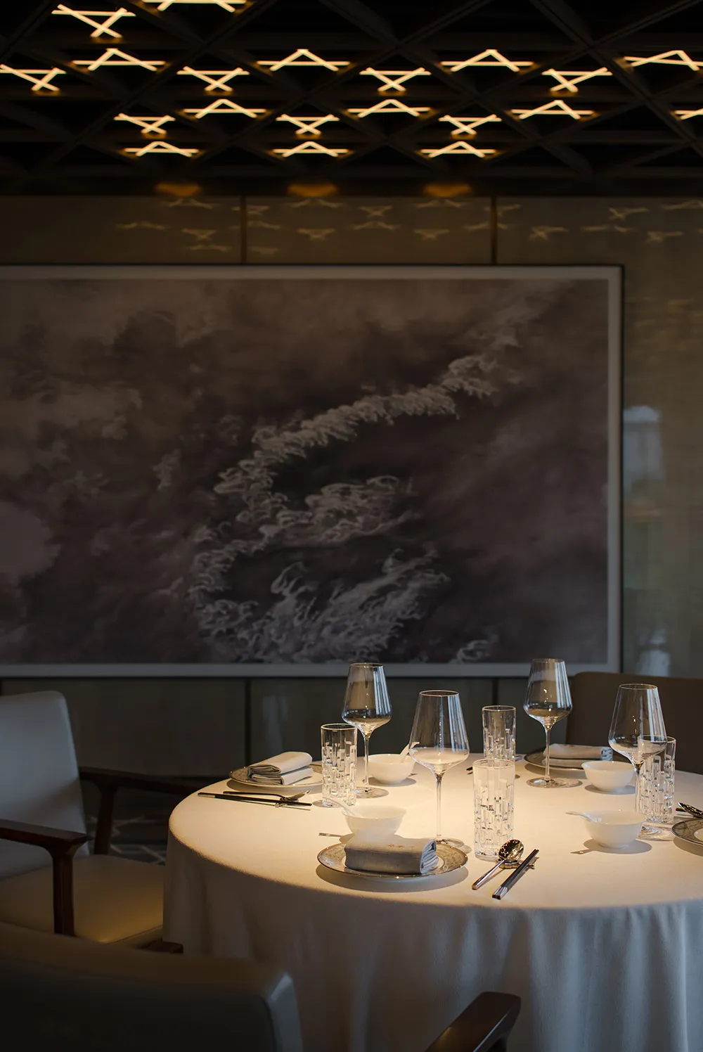 A luxurious dining area with a large table set for a meal, surrounded by chairs, wine glasses, and fine china