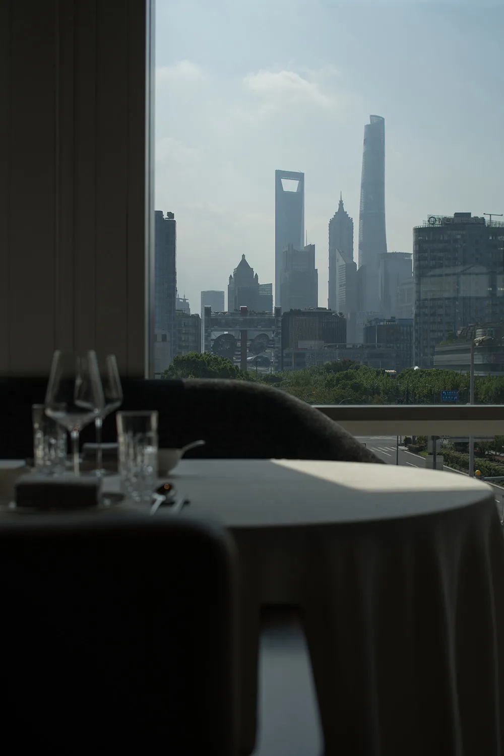 A rooftop dining space with a set table, wine glasses, and a city view from a high vantage point