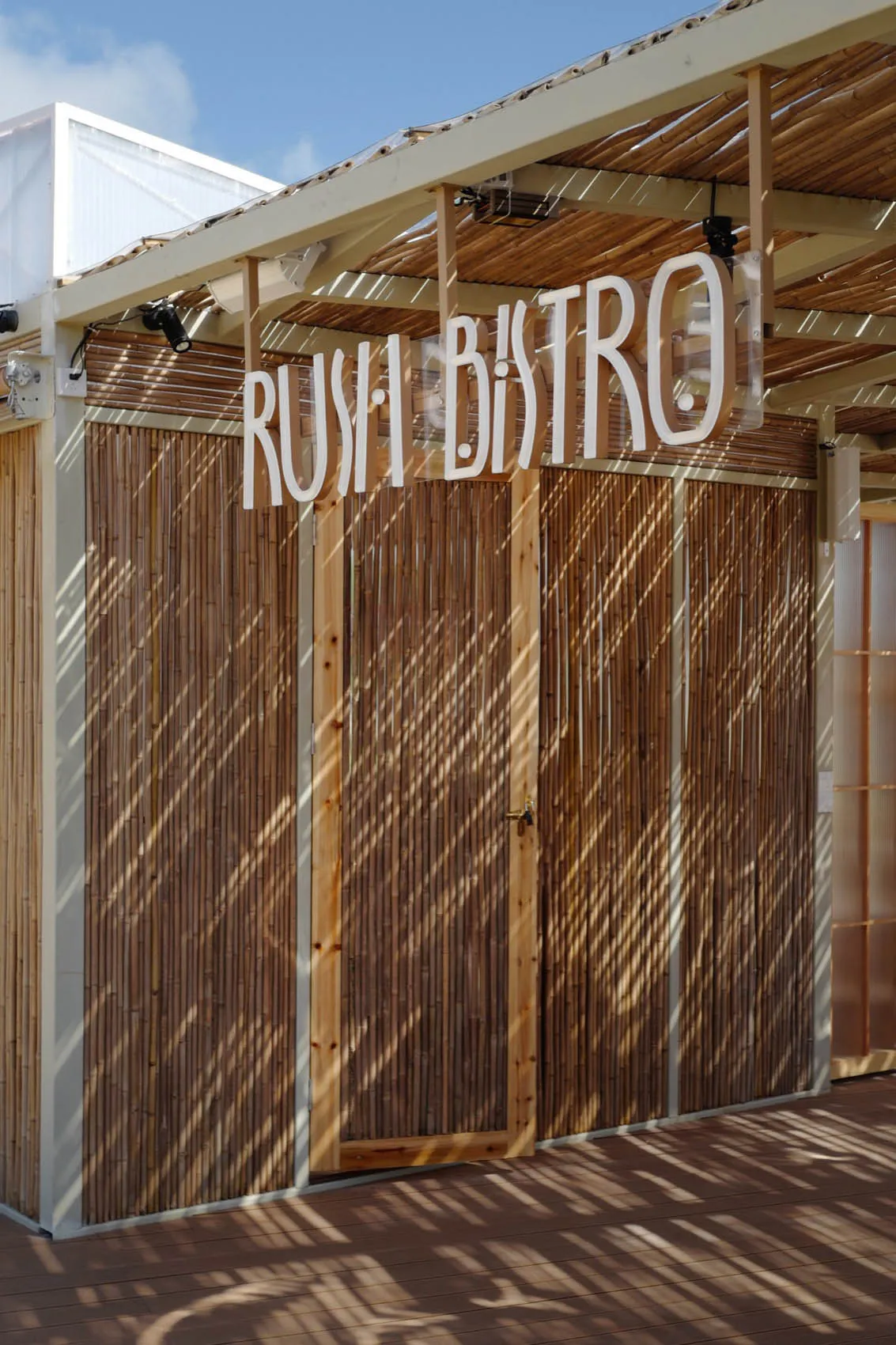 Outdoor restaurant with a wooden structure, bamboo doors, and natural light from open doors