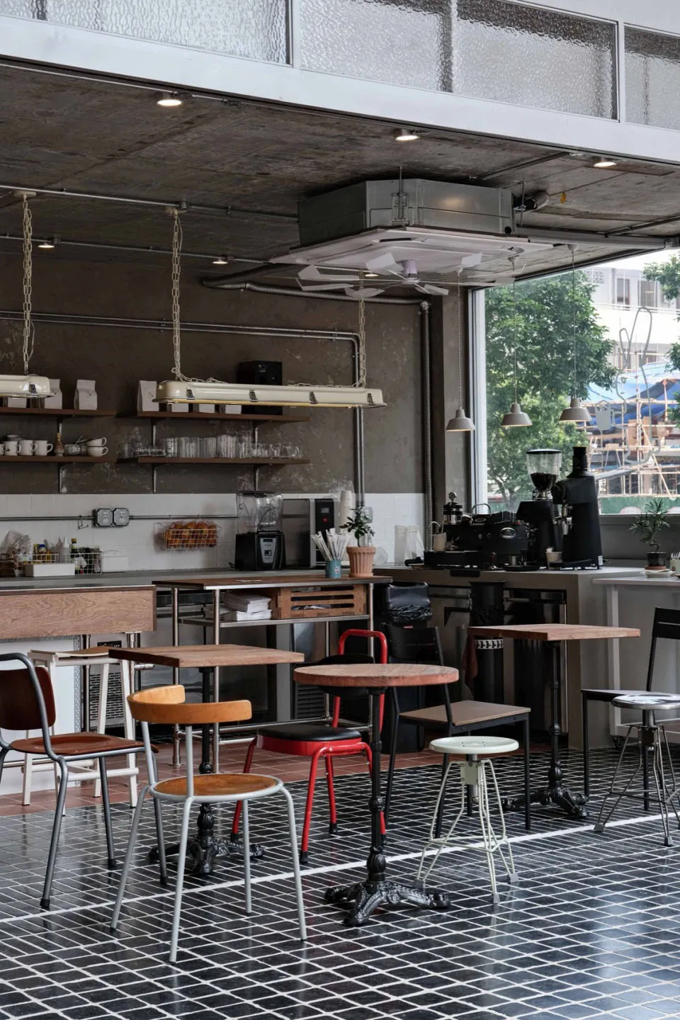 A kitchen with a large window, chairs, dining tables, potted plants, and kitchenware, set in a well-equipped space