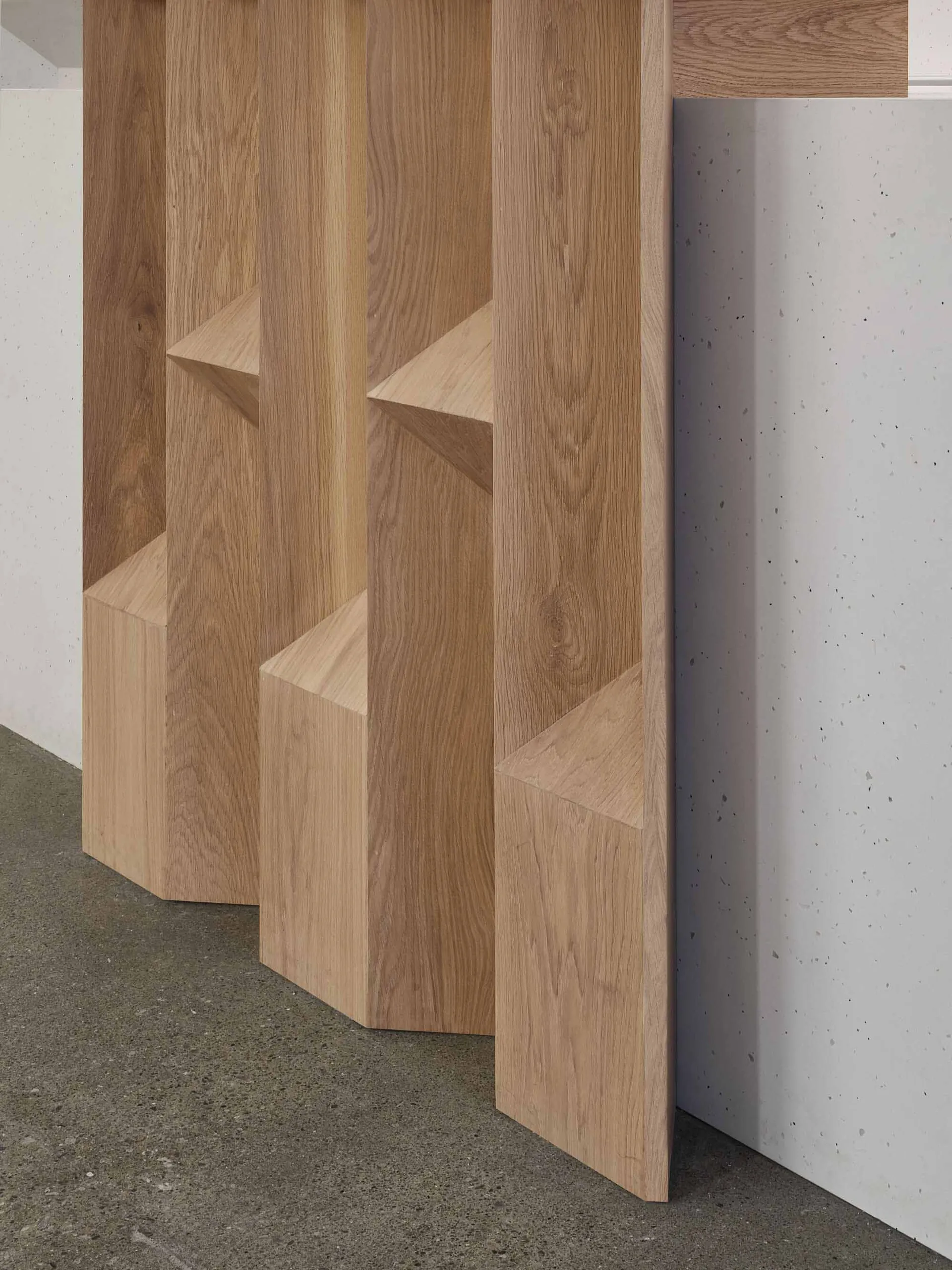 Three wooden bookshelves of varying heights against a white wall, creating a calm and organized atmosphere with neatly arranged books