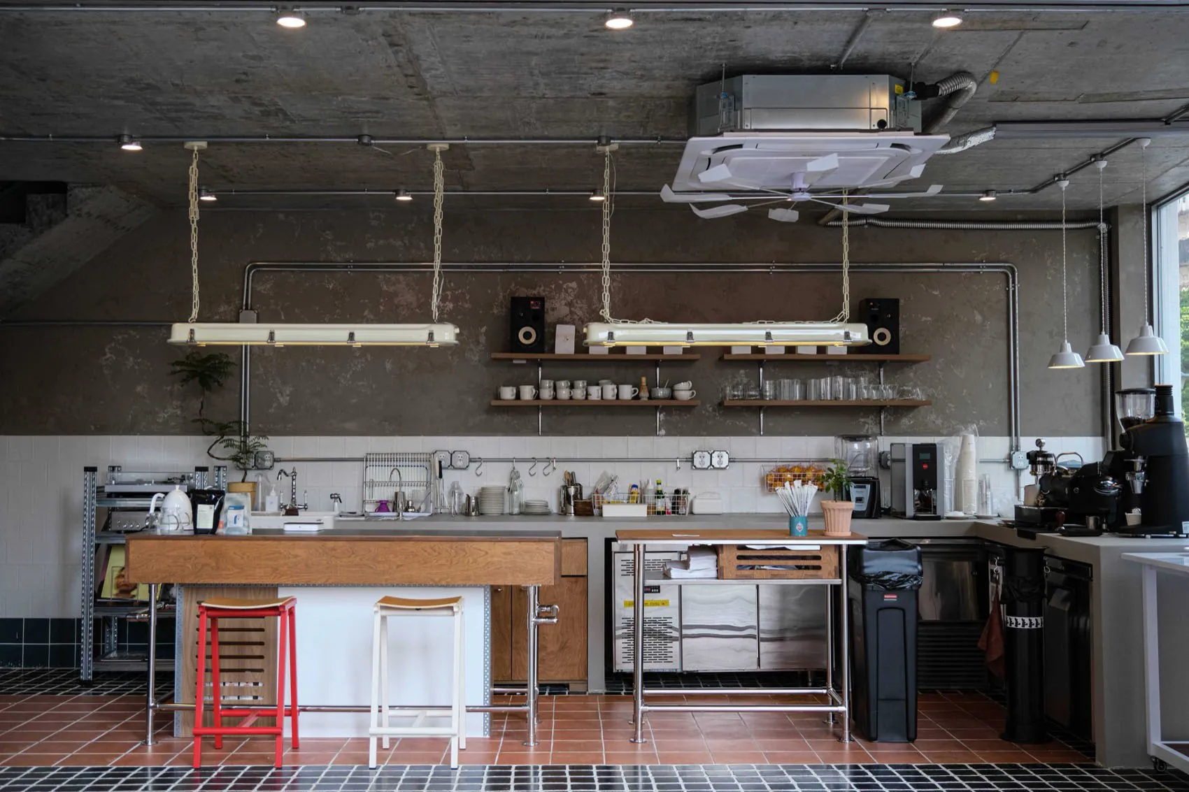 Industrial kitchen with stainless steel appliances, modern dining tables, and ample lighting