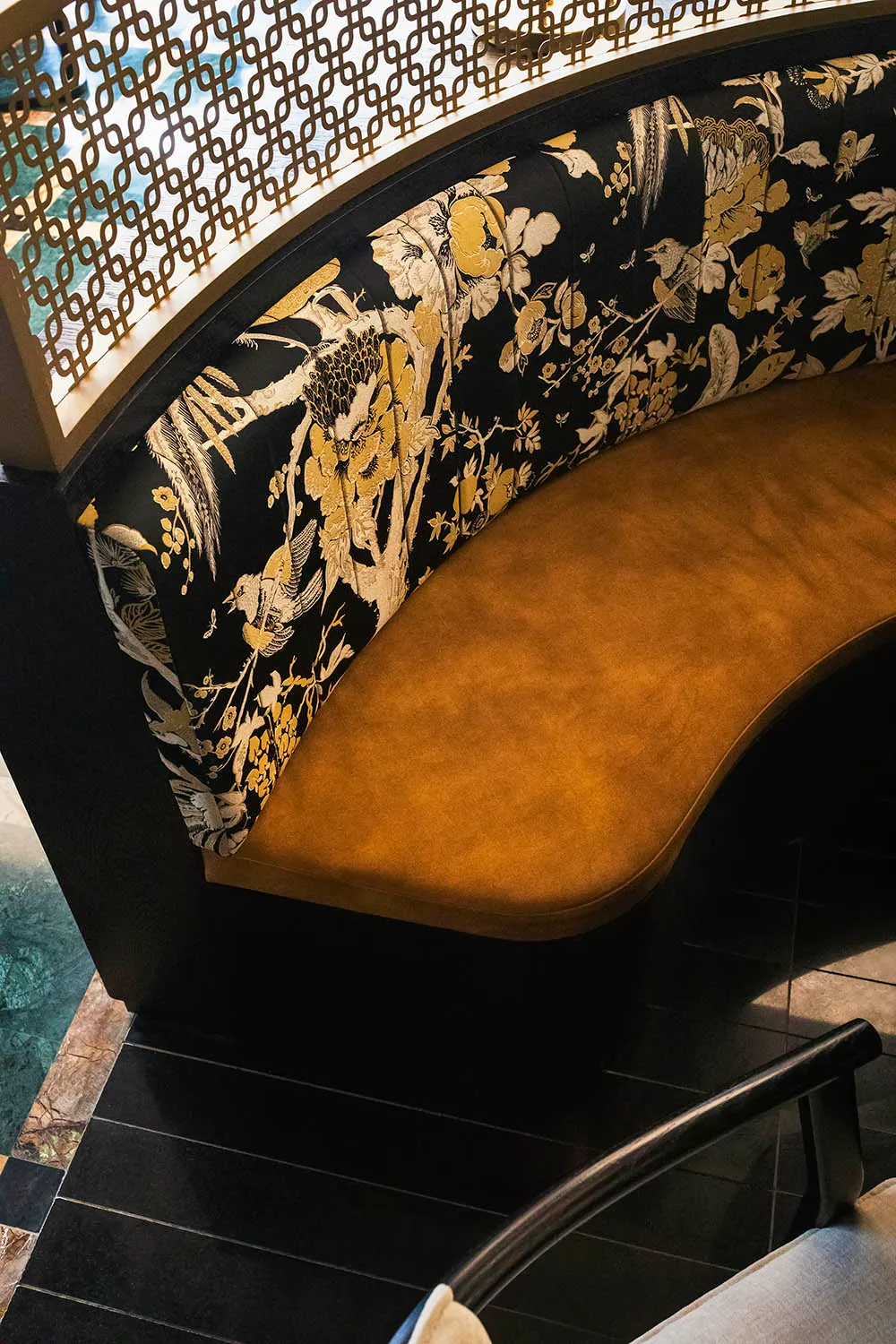 Ornate bench with floral design in a living area, possibly a dining room, with a black frame and Asian-inspired aesthetic