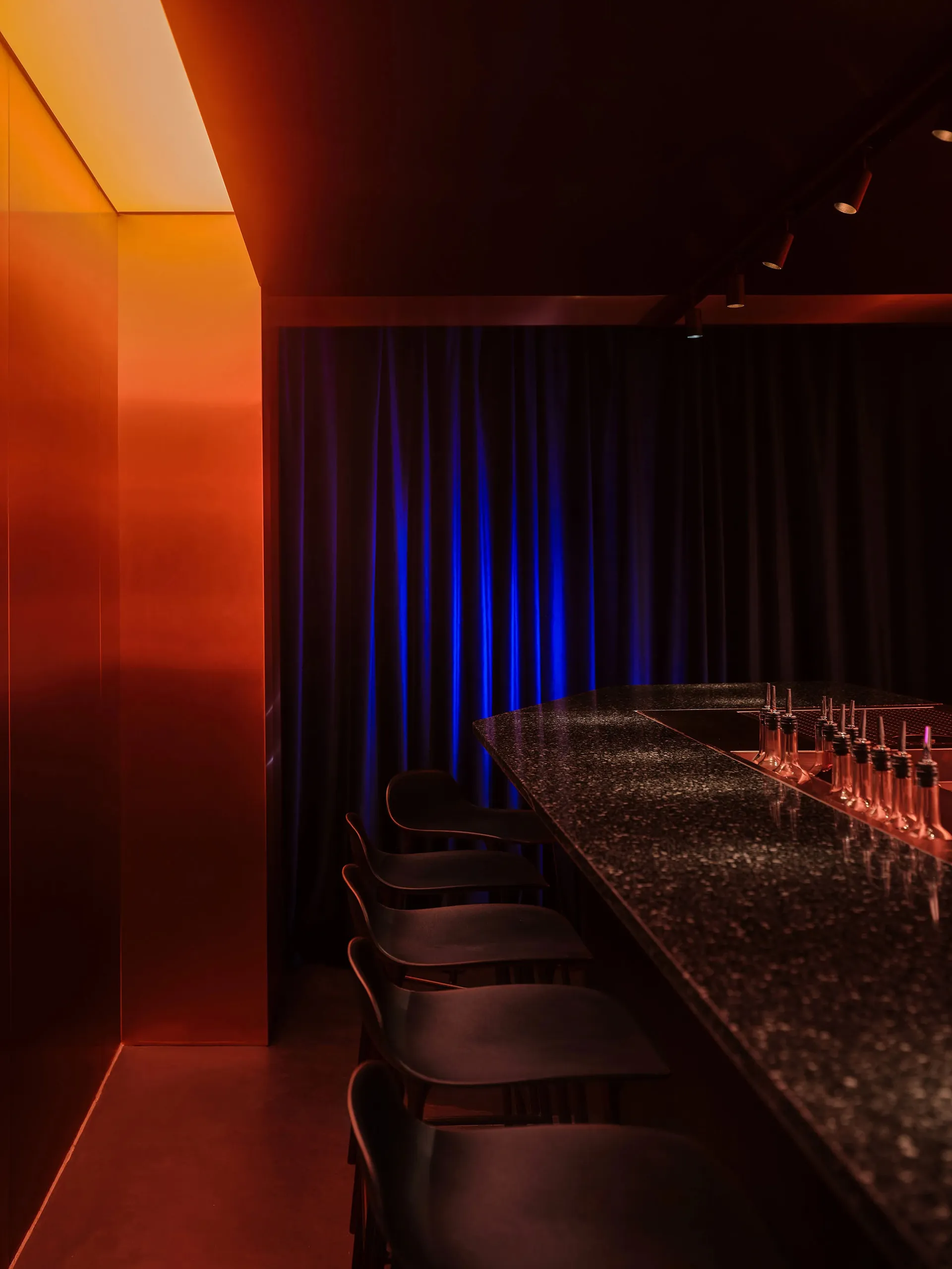 A modern counter with a marble top and three chairs, set in a sophisticated restaurant or lounge area