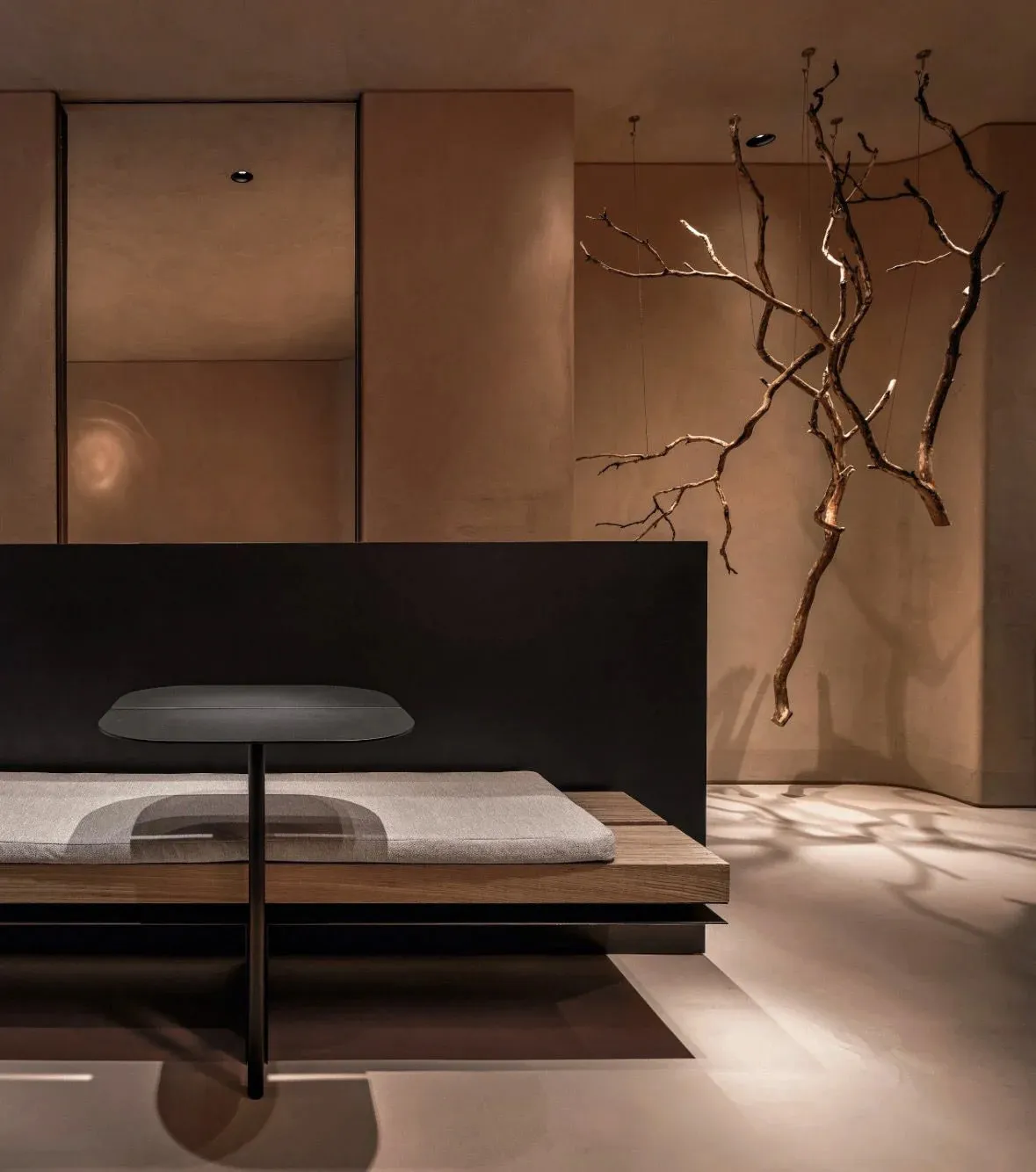 A modern bedroom with a black bed frame, wooden headboard, gray blanket, dining table, two chairs, and a potted plant, creating an open concept living area