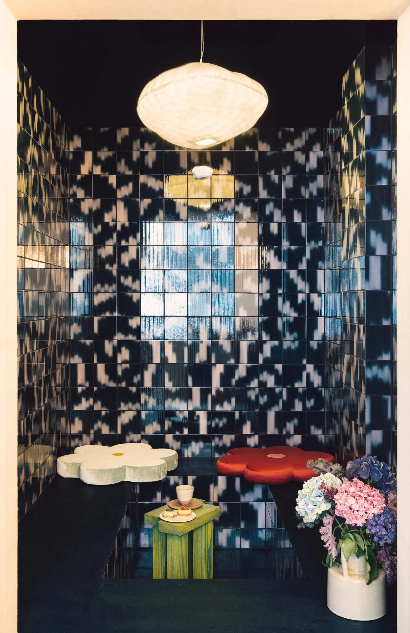 Modern showroom with a black and white checkered tile wall and a green and red checkered tabletop, featuring two chairs and a stylish atmosphere