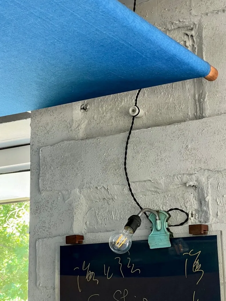 A blue curtain hangs on a brick wall with two old-fashioned lights attached, creating a unique interior design concept