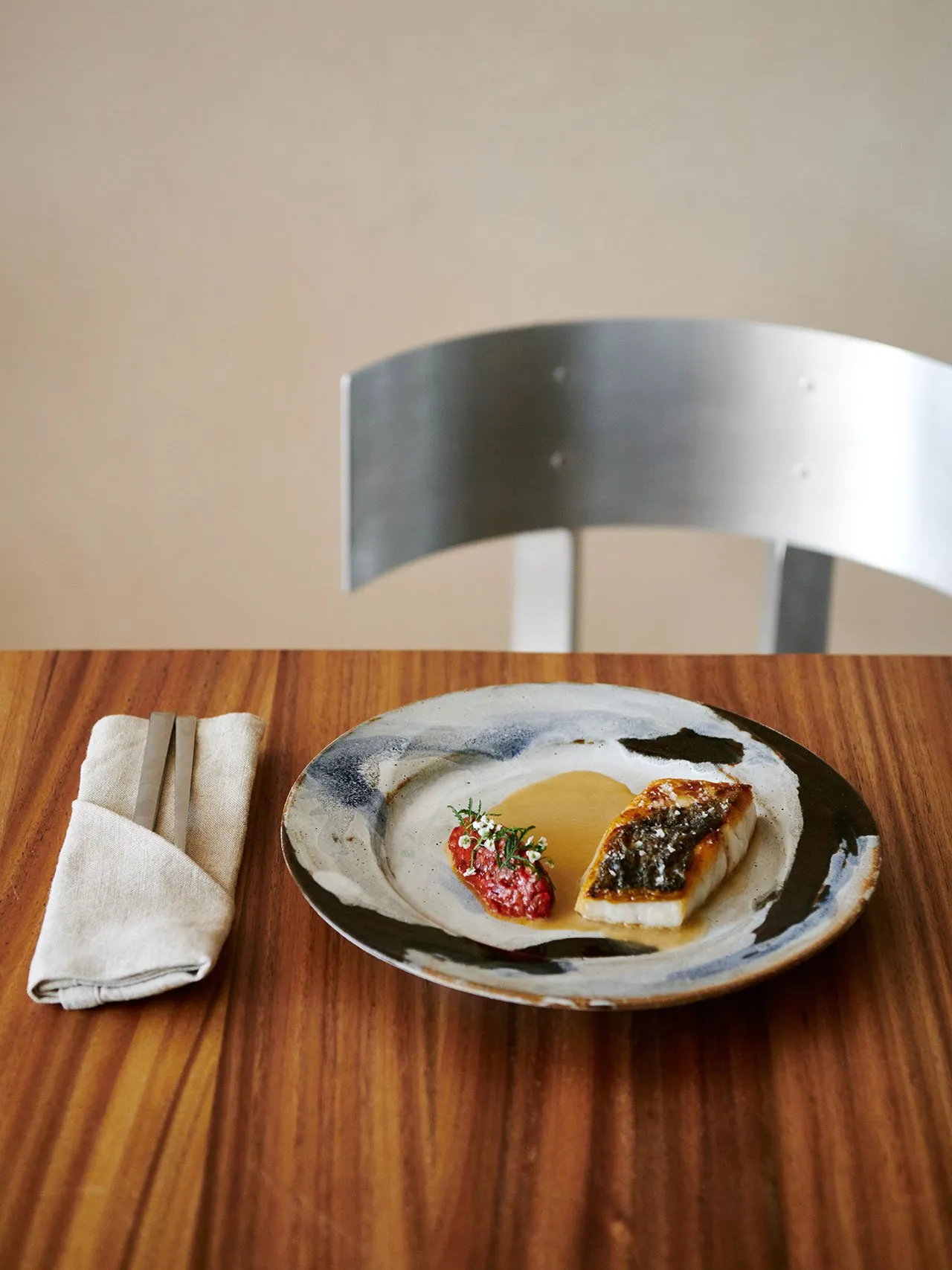 A wooden dining table set with a plate of food, two cups, a bowl, a fork, a knife, and a spoon, in a cozy and comfortable atmosphere