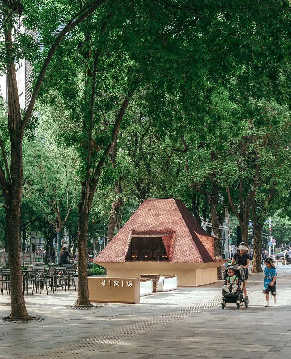 Outdoor area with benches, chairs, and a bicycle, surrounded by people enjoying a casual atmosphere