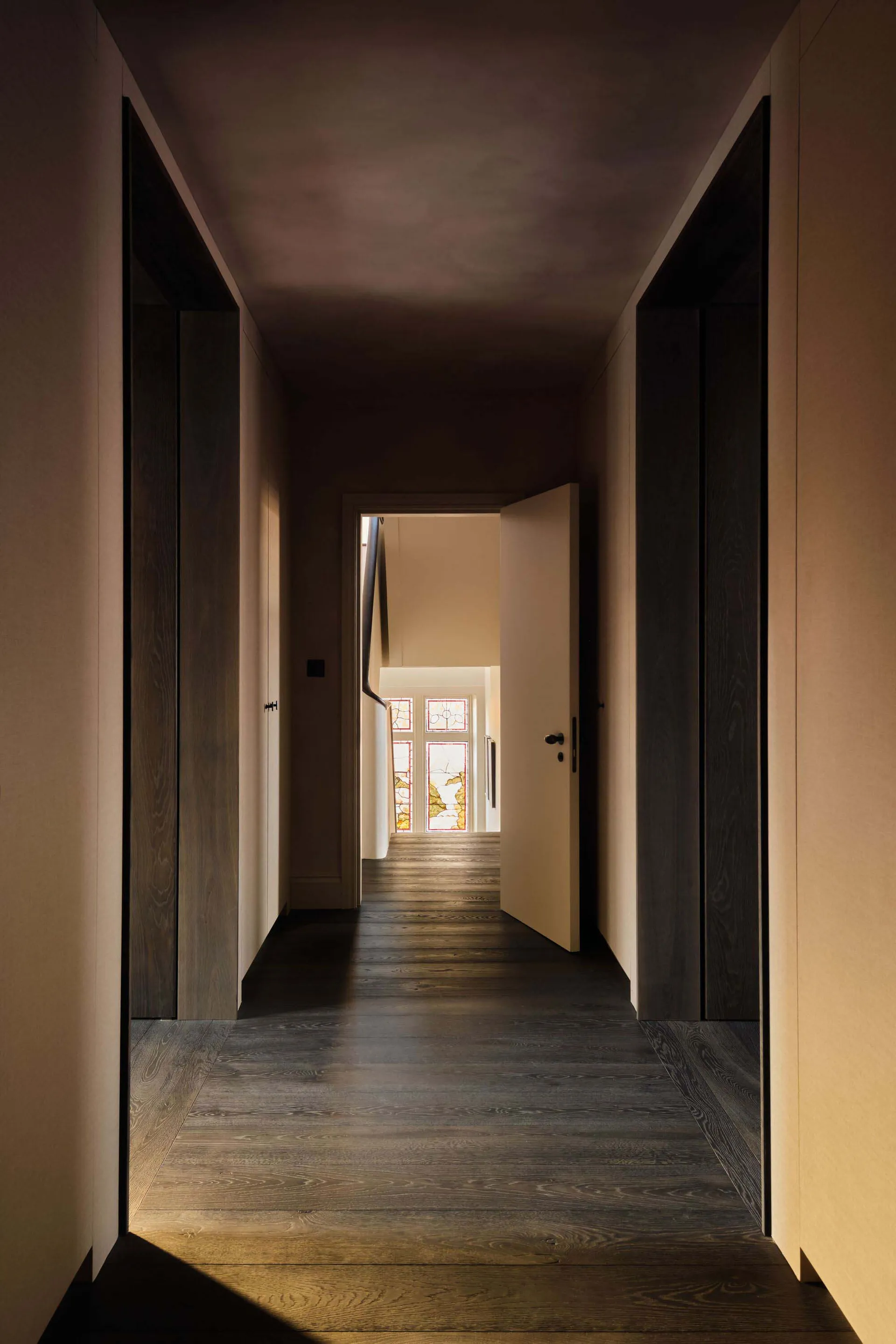 Empty hallway with wooden floors and walls, featuring a door and a window