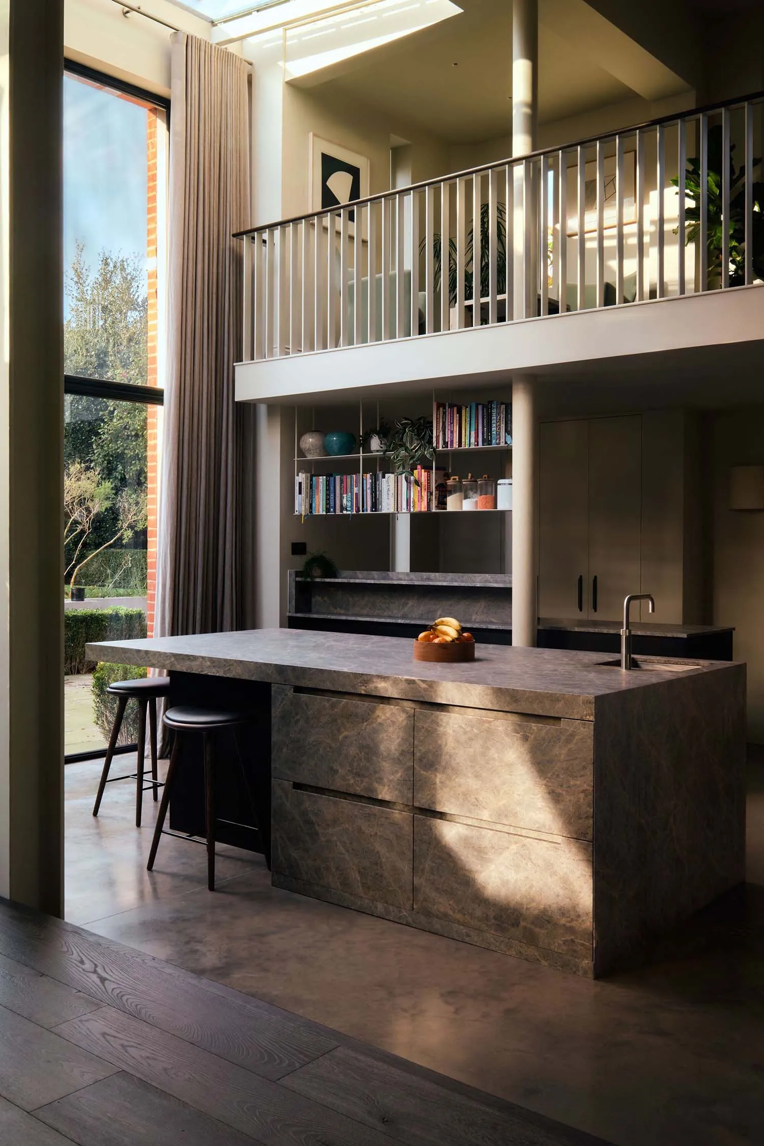 Modern kitchen and dining space with a large island countertop, sink, table, chairs, and scattered books, featuring a sleek and functional design