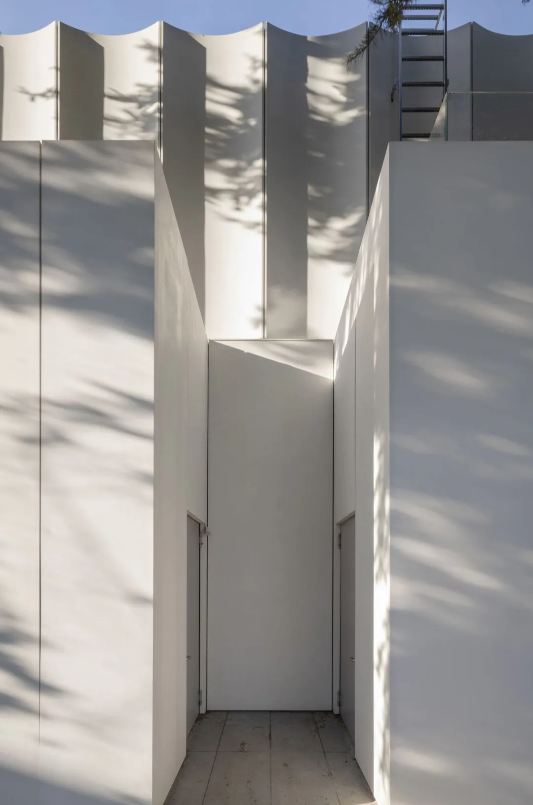 A serene entrance with two concrete pillars and an open doorway, set against a neutral background