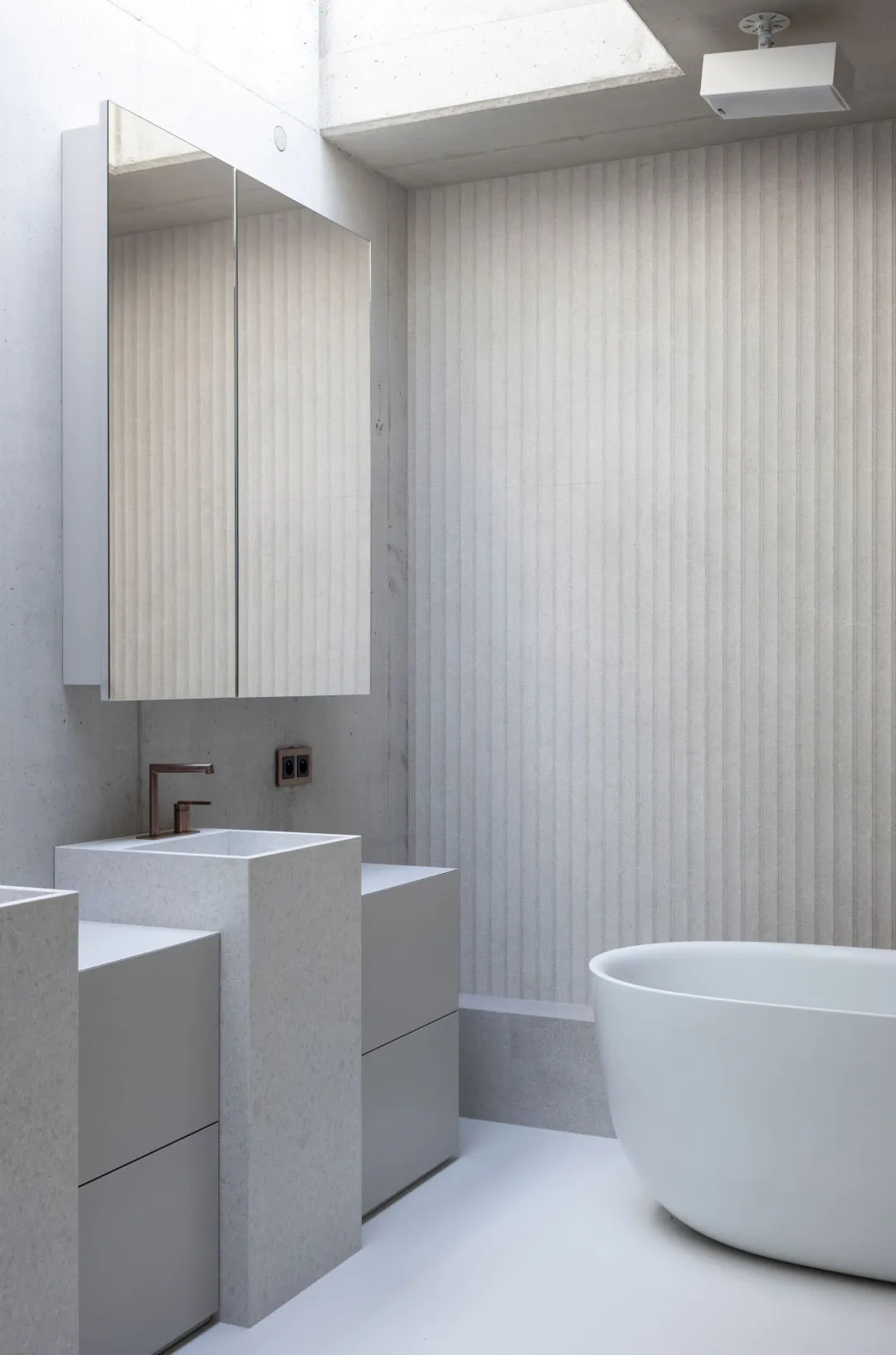 Bathroom with a white bathtub and two sinks, surrounded by striped wallpaper in a clean and well-maintained space