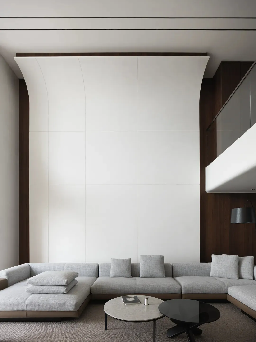Empty modern living room with a couch, chairs, and pillows, well-lit by natural sunlight through windows