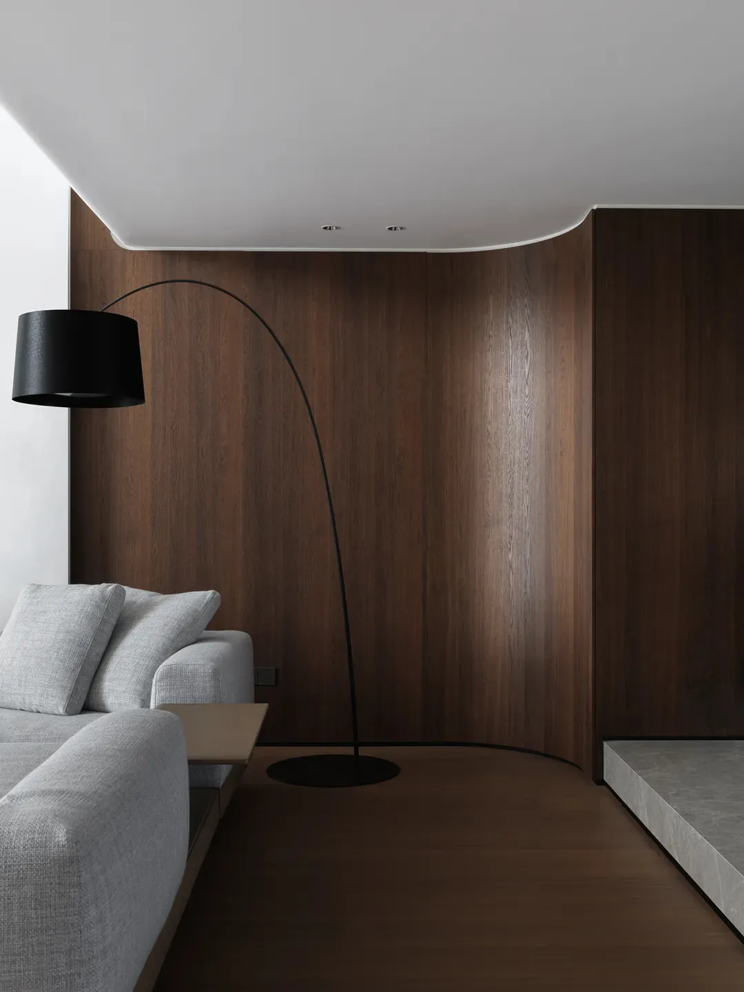 Cozy living area with a couch, chair, and lamp, surrounded by wooden panel walls and illuminated by a prominent lamp