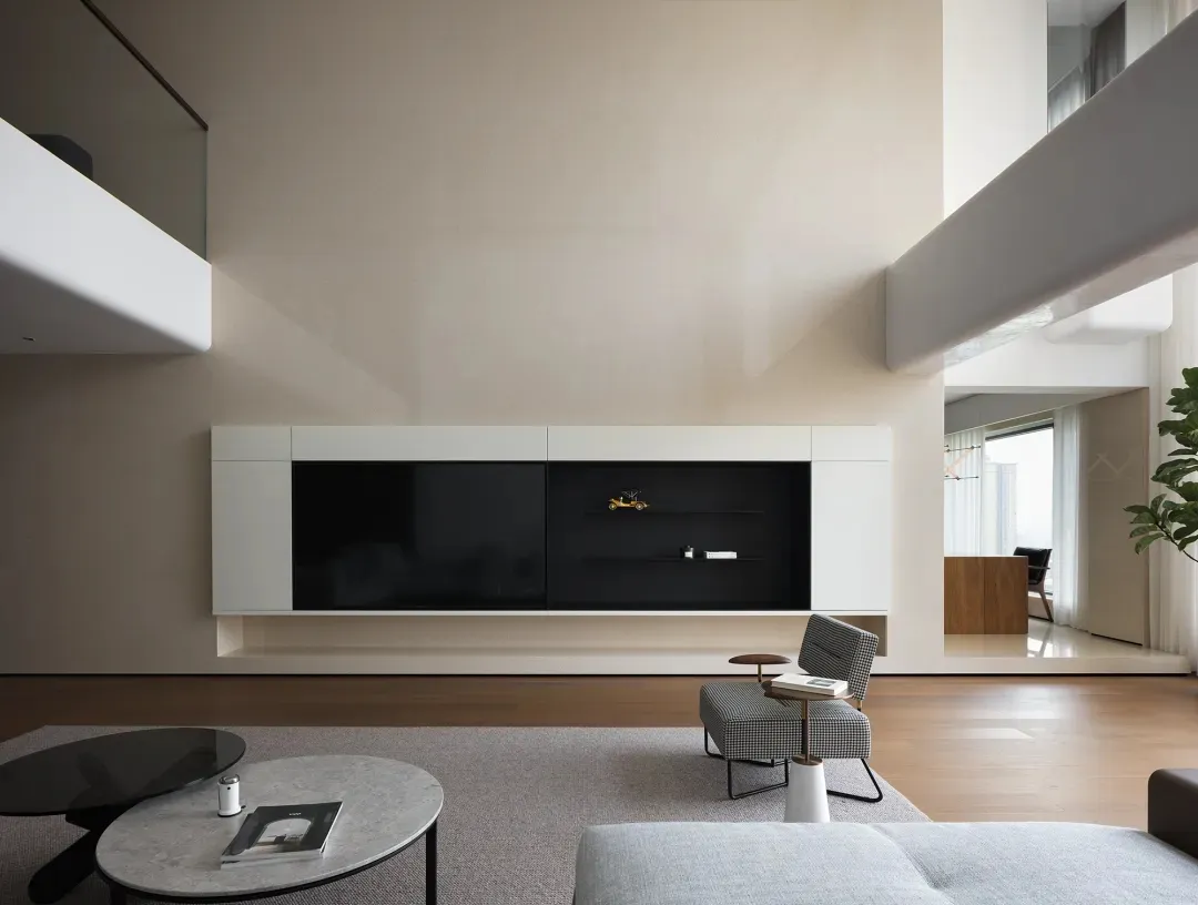 Open modern living area with a flat screen TV, chairs, and a couch, surrounded by clean lines and minimalistic decoration