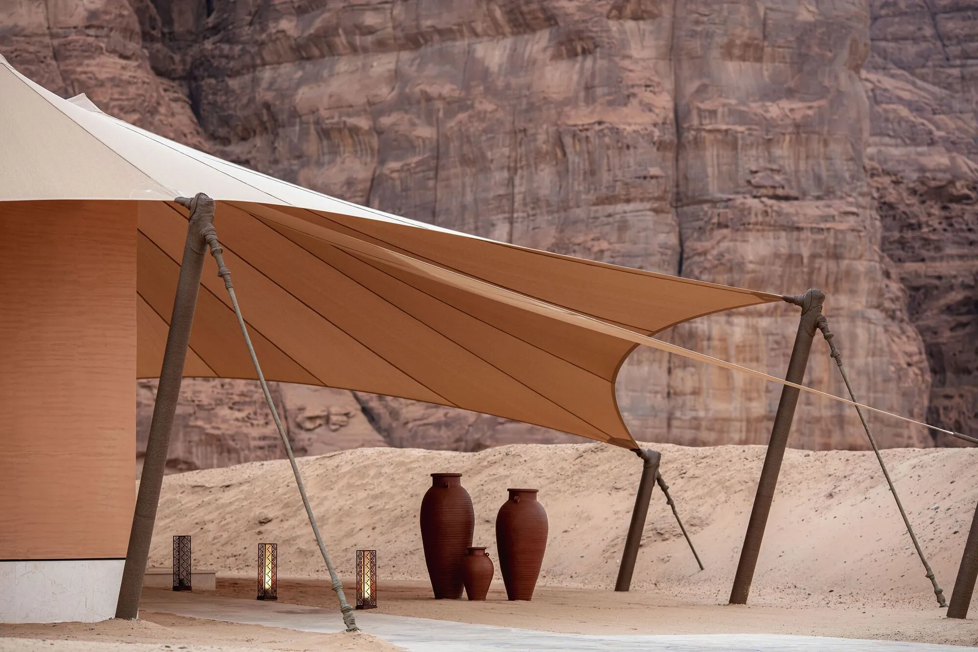 A shaded outdoor area with a tent-like structure, three large vases, and a relaxing atmosphere