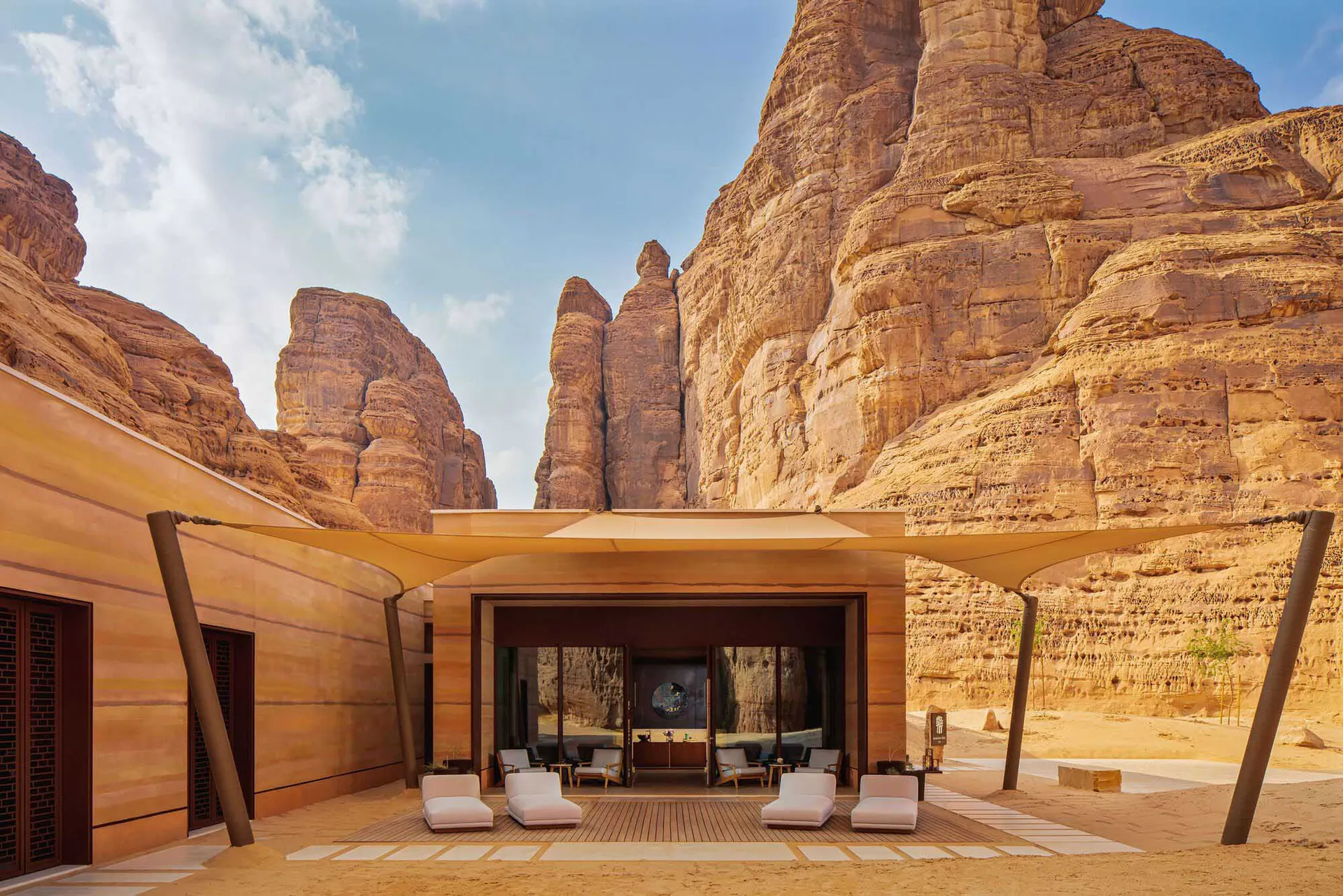 A comfortable outdoor living space with wood furniture, TVs, and a dining table, set amidst a serene atmosphere