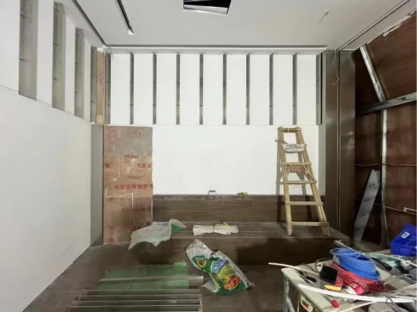 A room under construction with wooden flooring, a staircase, and two ladders, giving a glimpse into a workspace or building site