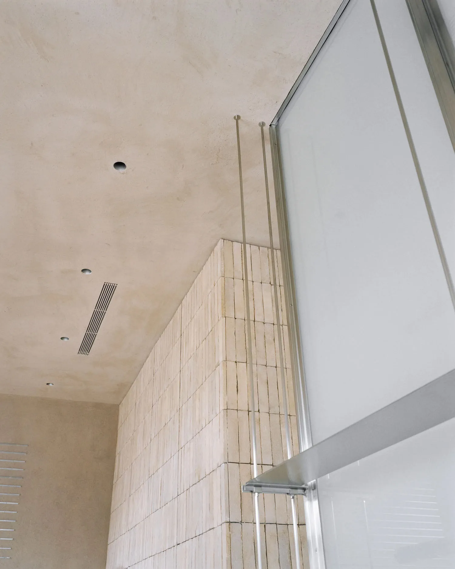 Modern hotel lobby with a glass door, brick wall, and tile accents, featuring a stylish and spacious design