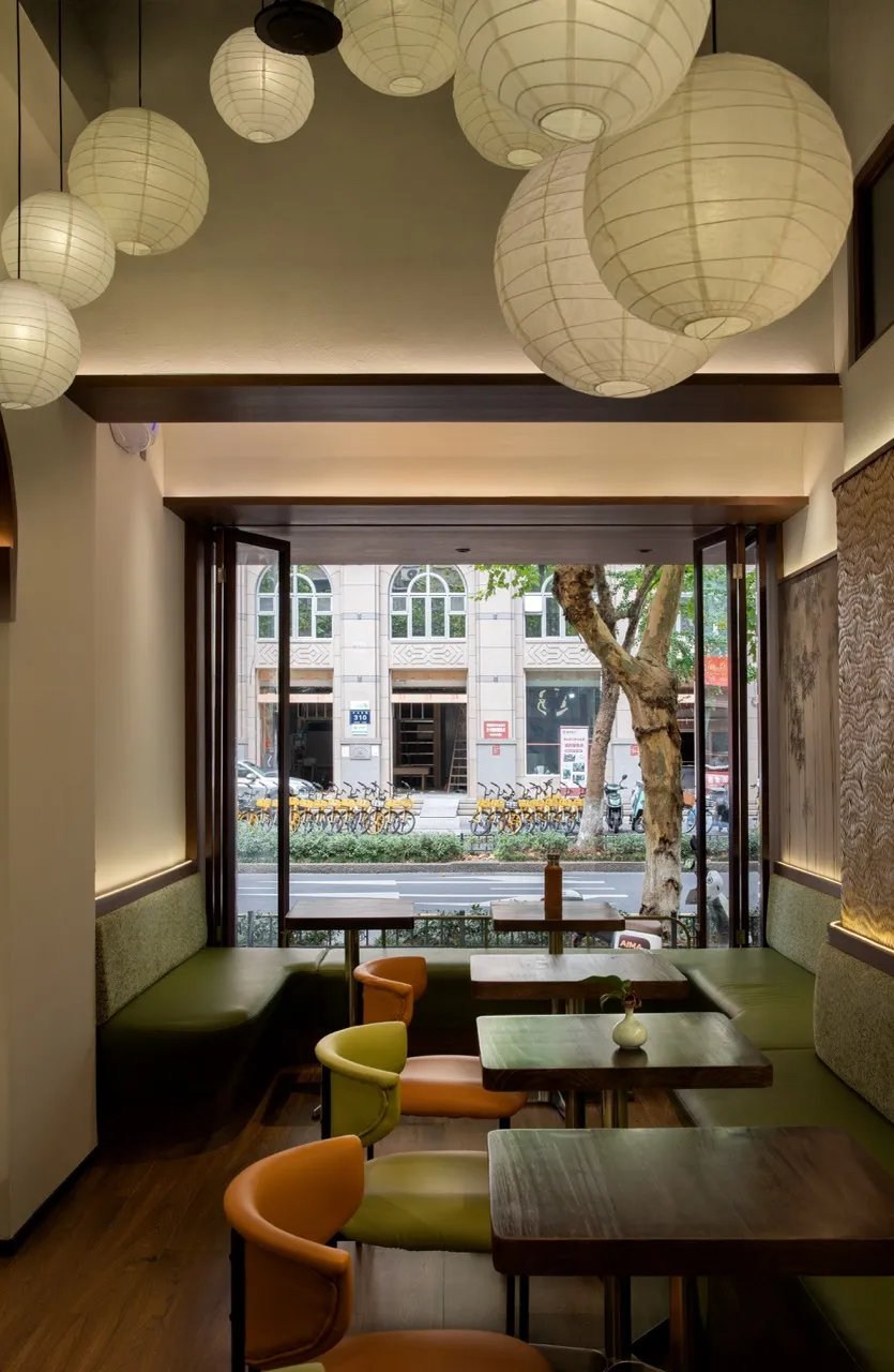 Modern restaurant interior with wood paneling, tables, chairs, and potted plants, creating a warm and inviting atmosphere