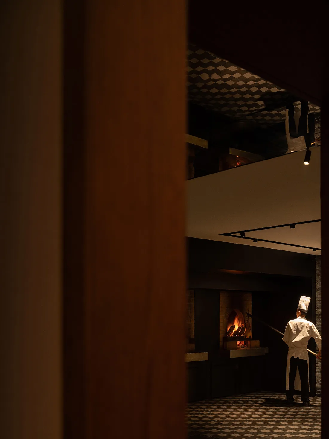 A quiet kitchen scene with a man standing in front of an open fireplace, surrounded by a warm and inviting atmosphere