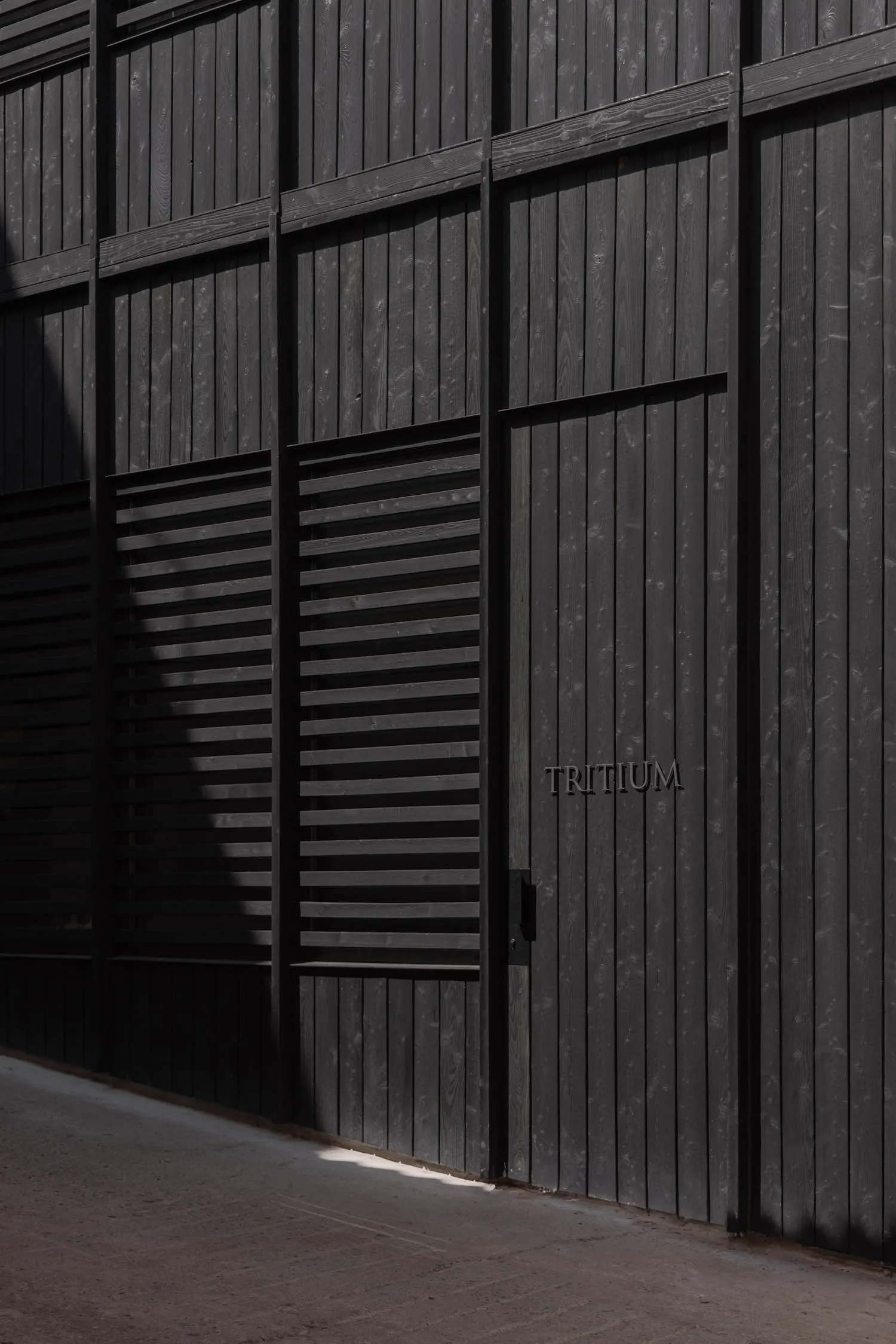 A dark and mysterious exterior building facade with a black door and a white sign, set against a dimly lit background