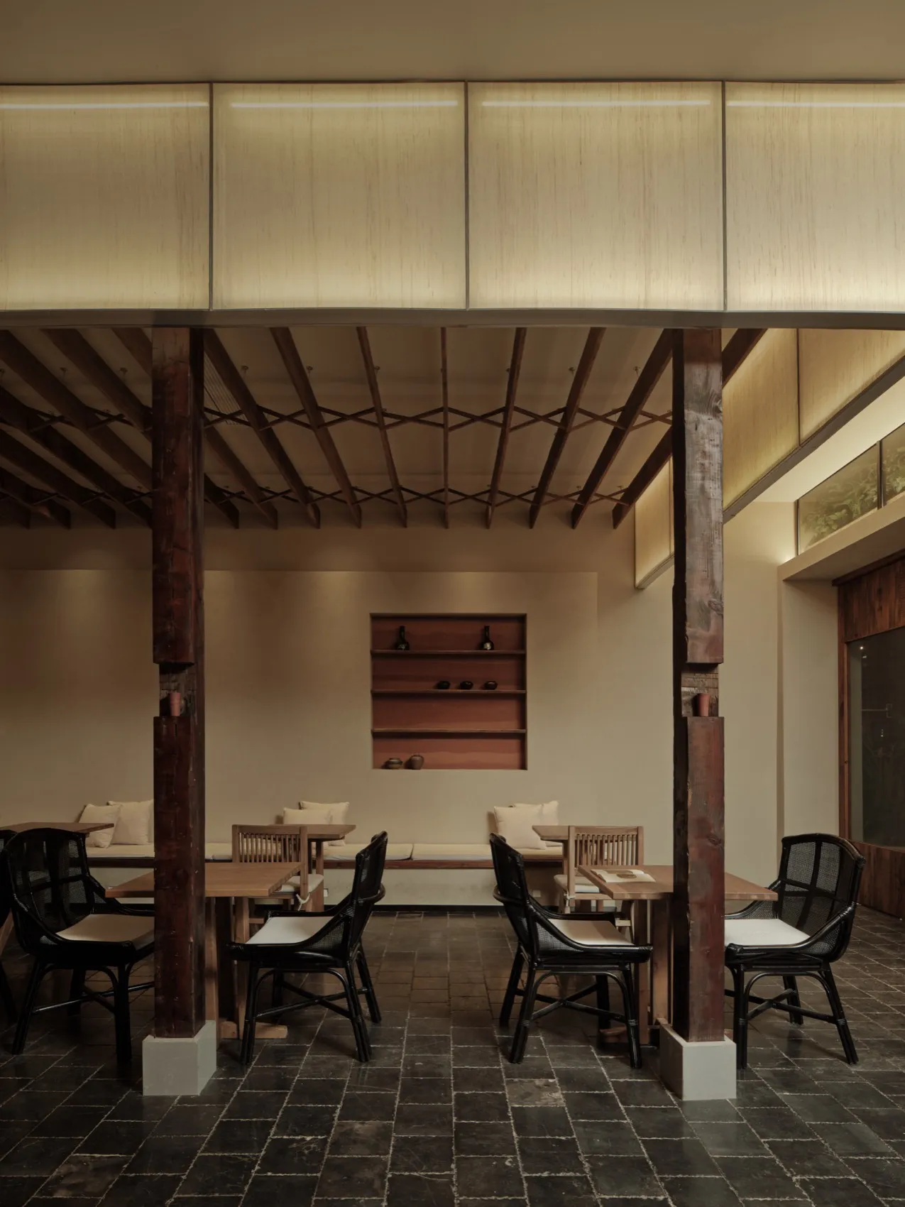 Cozy restaurant interior with wooden beams, dim lighting, and wine glasses on tables