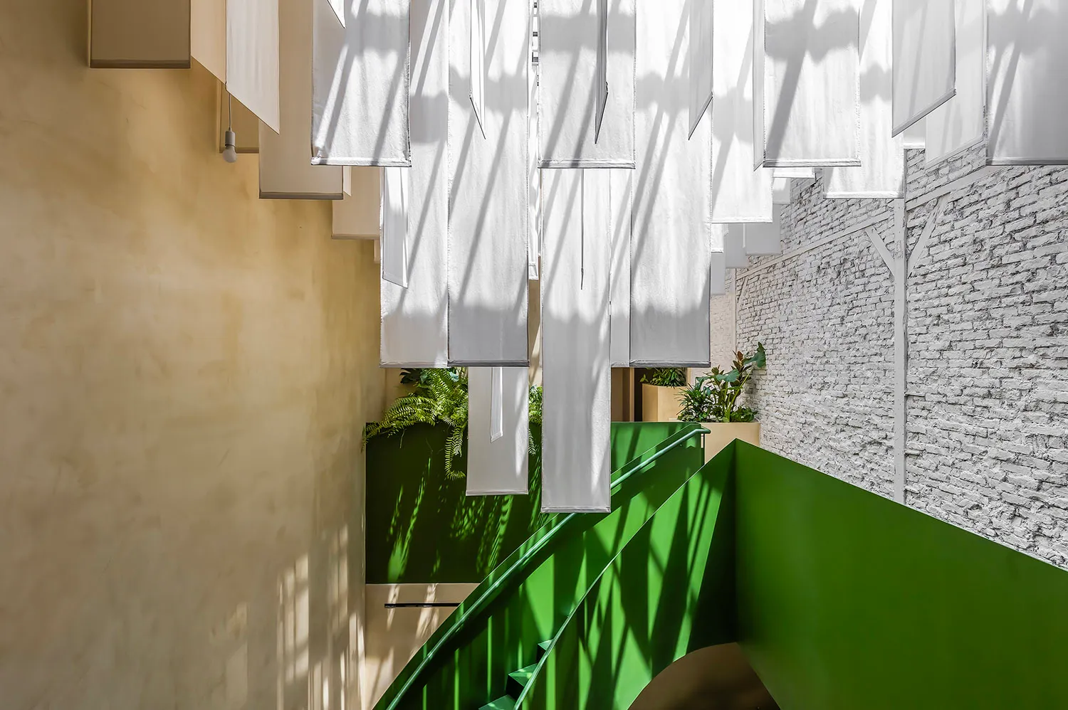 A bright and inviting space with a staircase leading to a green area, featuring white curtains and a sense of elegance