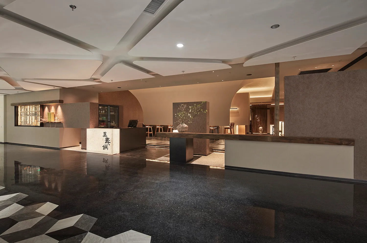 A hotel lobby with a large open area, a counter, chairs, and a potted plant, creating a welcoming atmosphere for guests