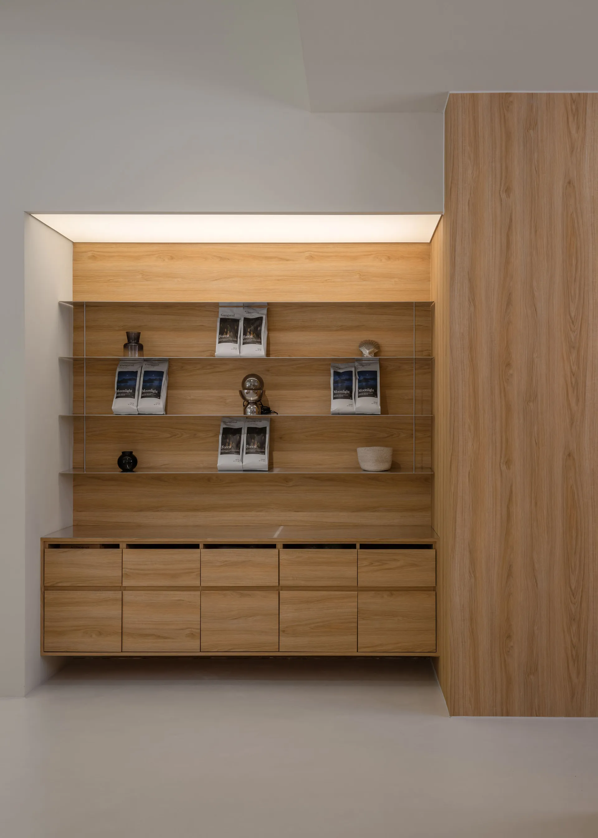 A wooden bookshelf with a brown finish, placed in a room with a white wall, holding neatly arranged books