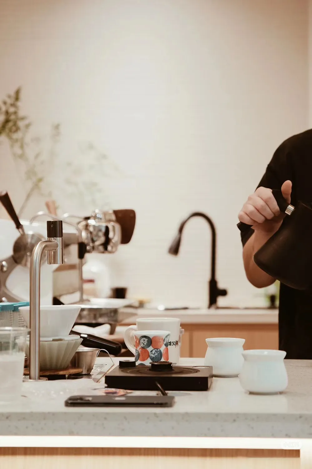 A casual kitchen with a focus on functionality, featuring a wood and metal construction, with appliances, cups, and utensils on the countertop