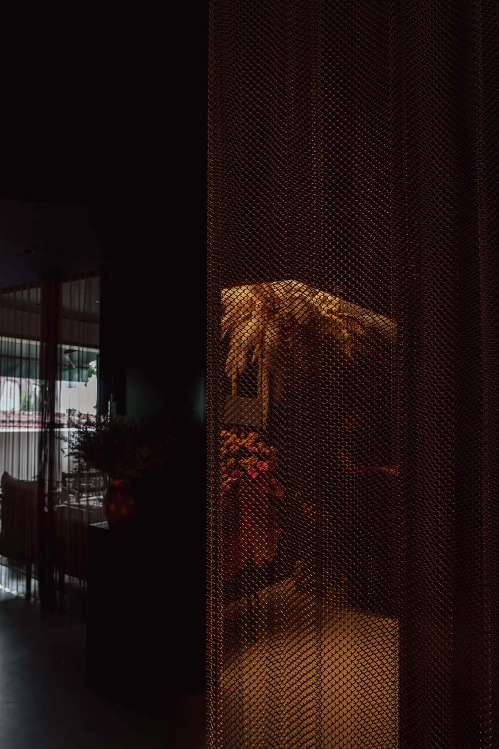 A cozy room with a floral patterned curtain, potted plants, and decorative vases, suggesting a living or dining space