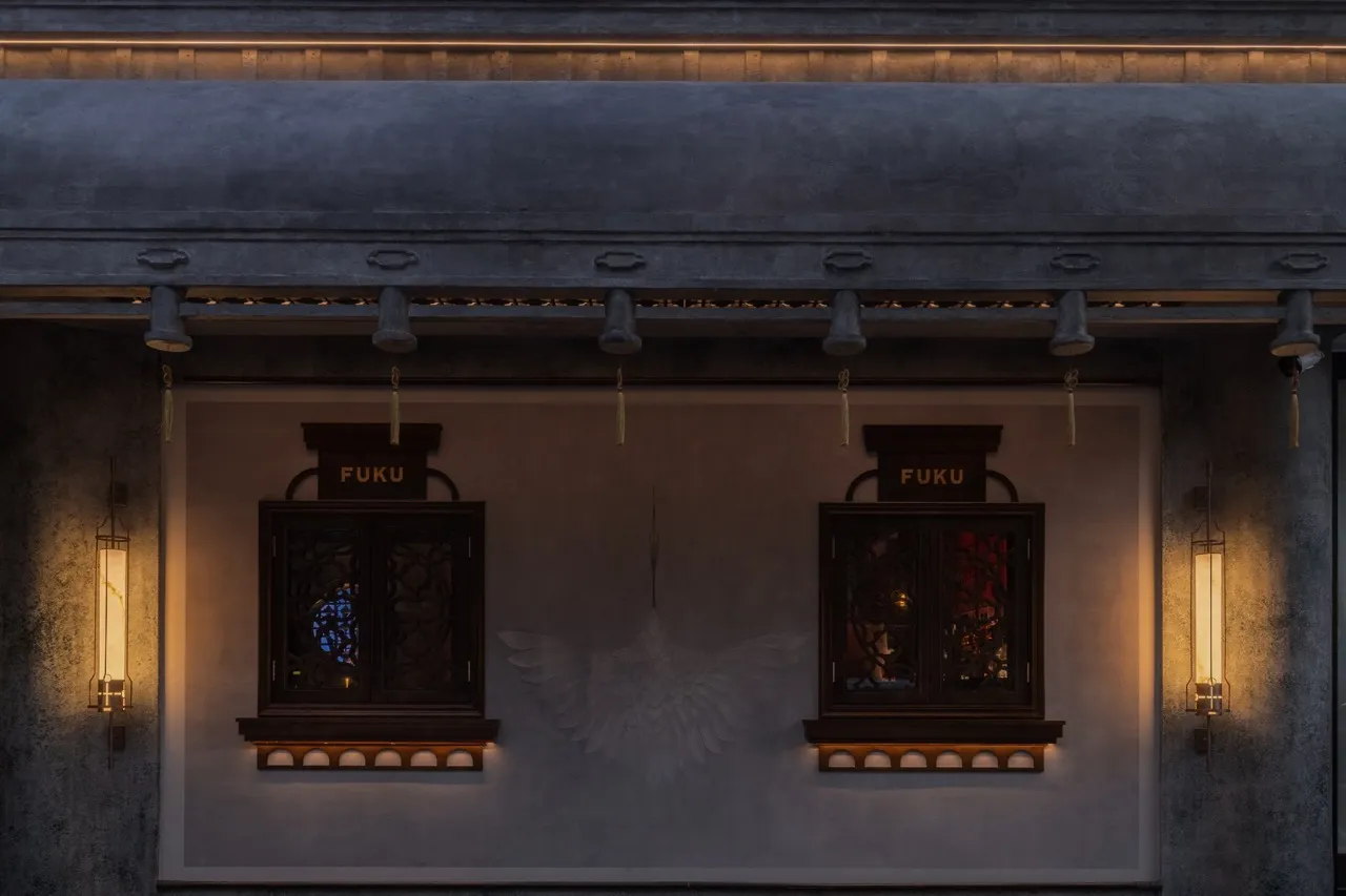 Gray building with ornate windows featuring a bird motif, set against a neutral background