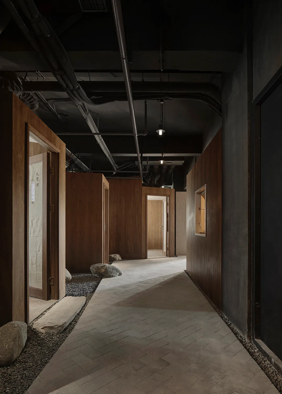 Dimly lit hallway with wooden doors, rocks on the floor, and a mysterious atmosphere