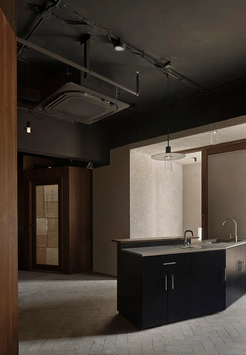 Empty kitchen with cement block walls, a sink, countertop, and cabinets, with a bottle on the counter