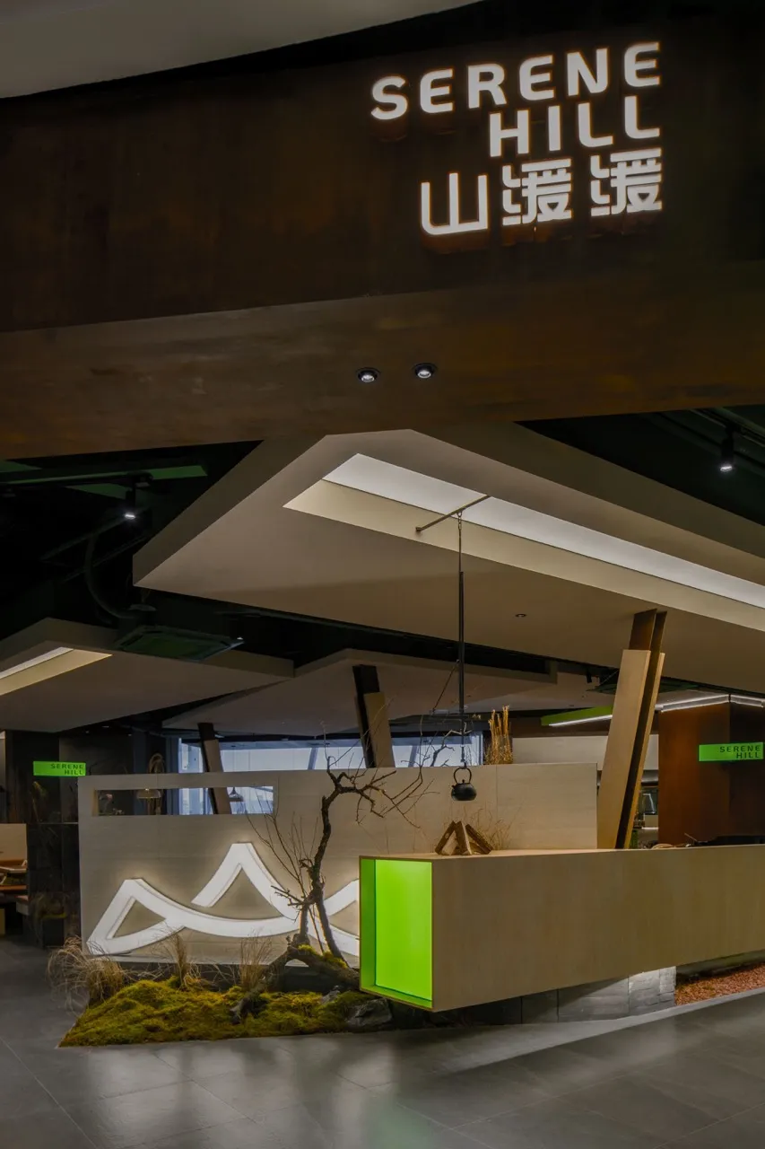 Modern showroom with white and green walls, natural light, and potted plants, featuring a mix of seating areas and clean lines