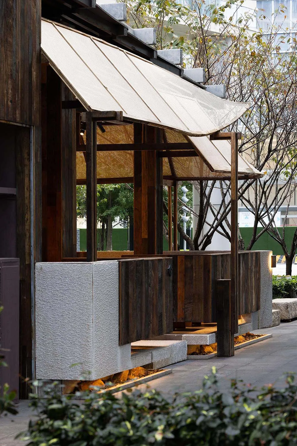 An open-air restaurant with wooden walls and a thatched roof, featuring two wooden benches and a relaxed atmosphere