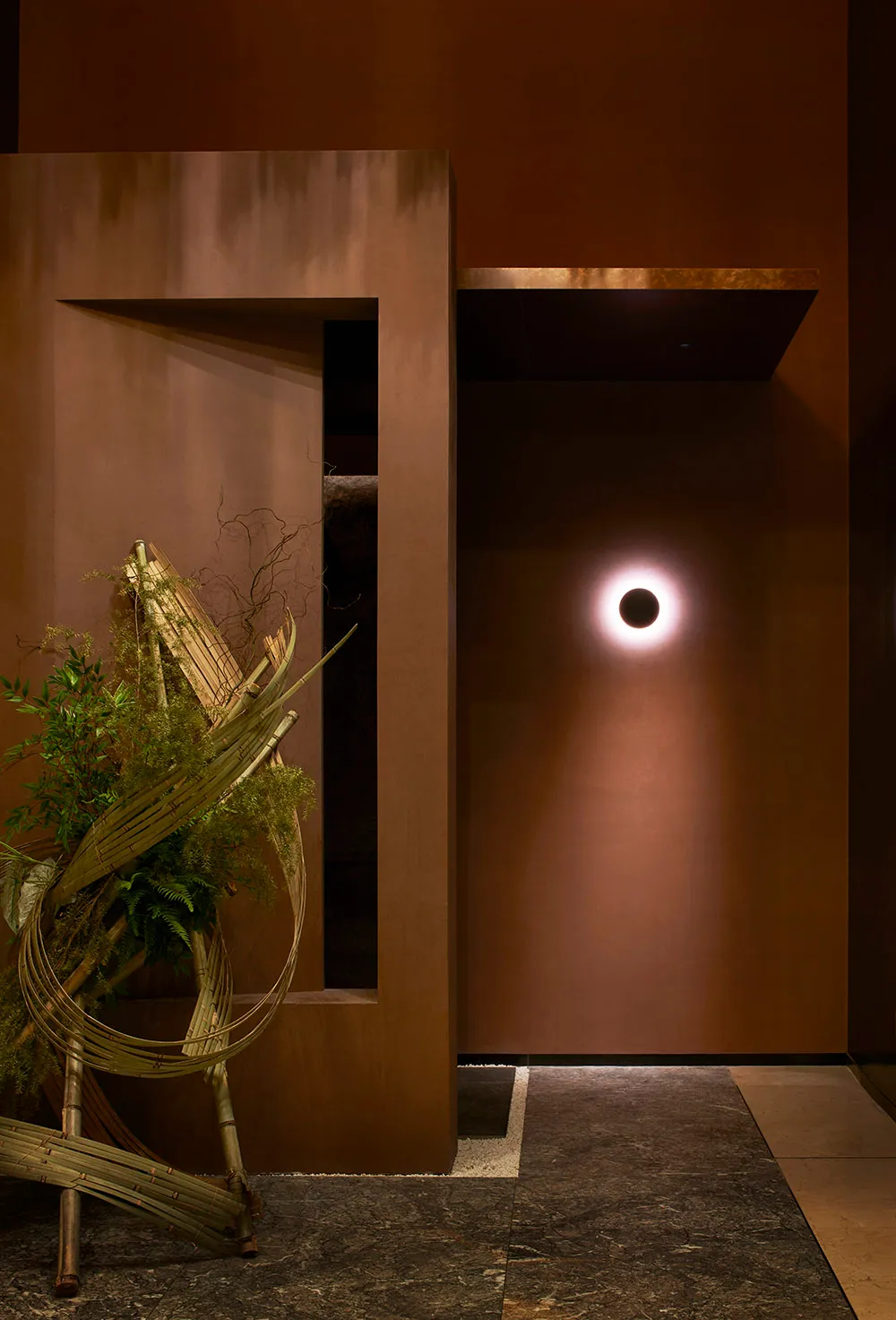 Warm and inviting interior space with a brown wall, potted plants, and a vase, featuring earthy tones and natural elements